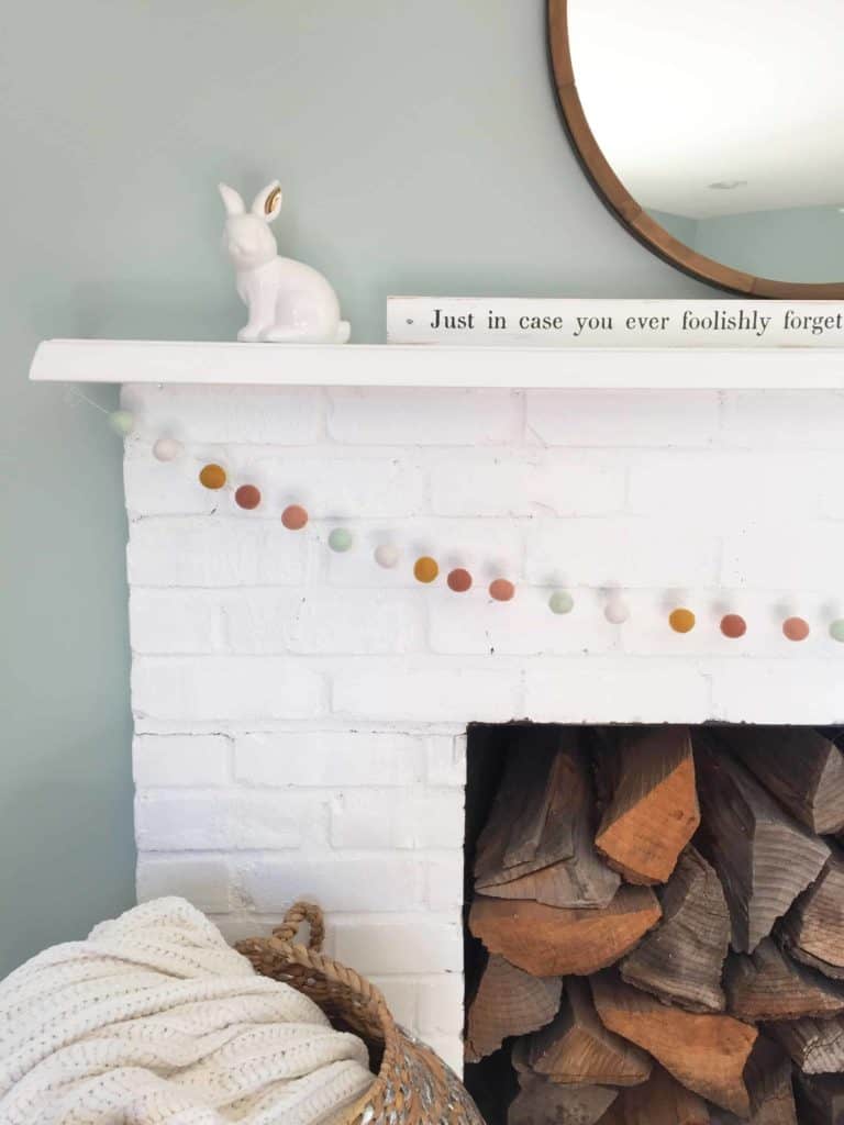 white painted brick fireplace with aqua glass jars and white ceramic bunny