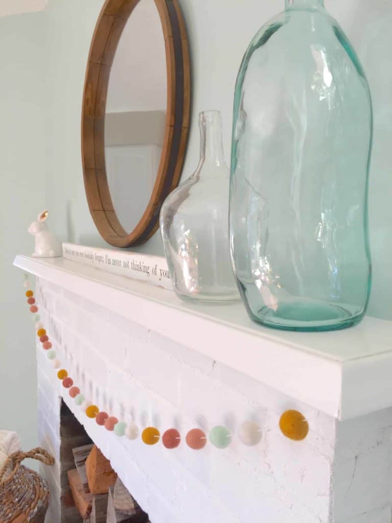 white painted brick fireplace with aqua glass jars and white ceramic bunny