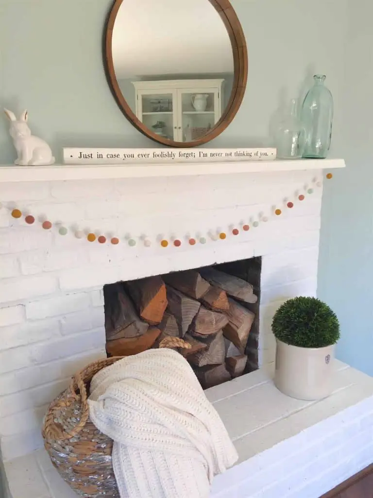 white painted brick fireplace with aqua glass jars and white ceramic bunny
