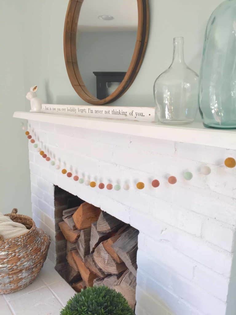 white painted brick fireplace with aqua glass jars and white ceramic bunny