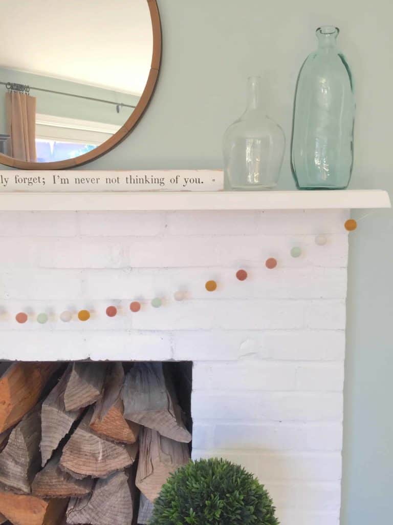 white painted brick fireplace with aqua glass jars and white ceramic bunny