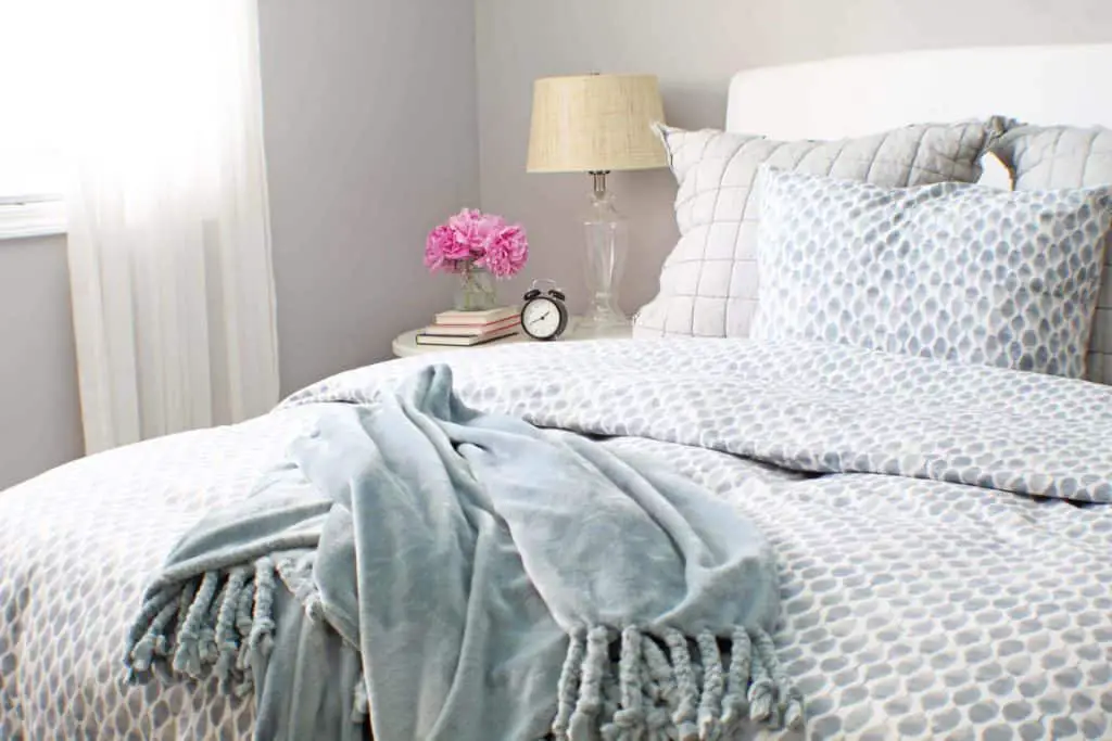 white upholstered headboard and blue west elm bedding 