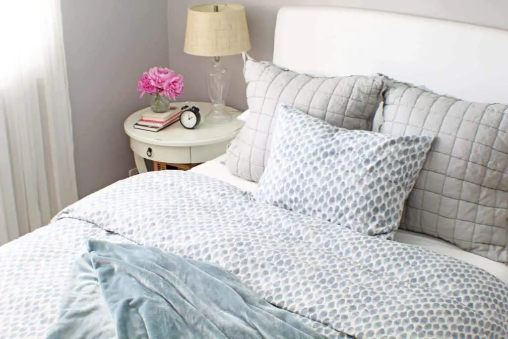 white upholstered headboard and blue west elm bedding 