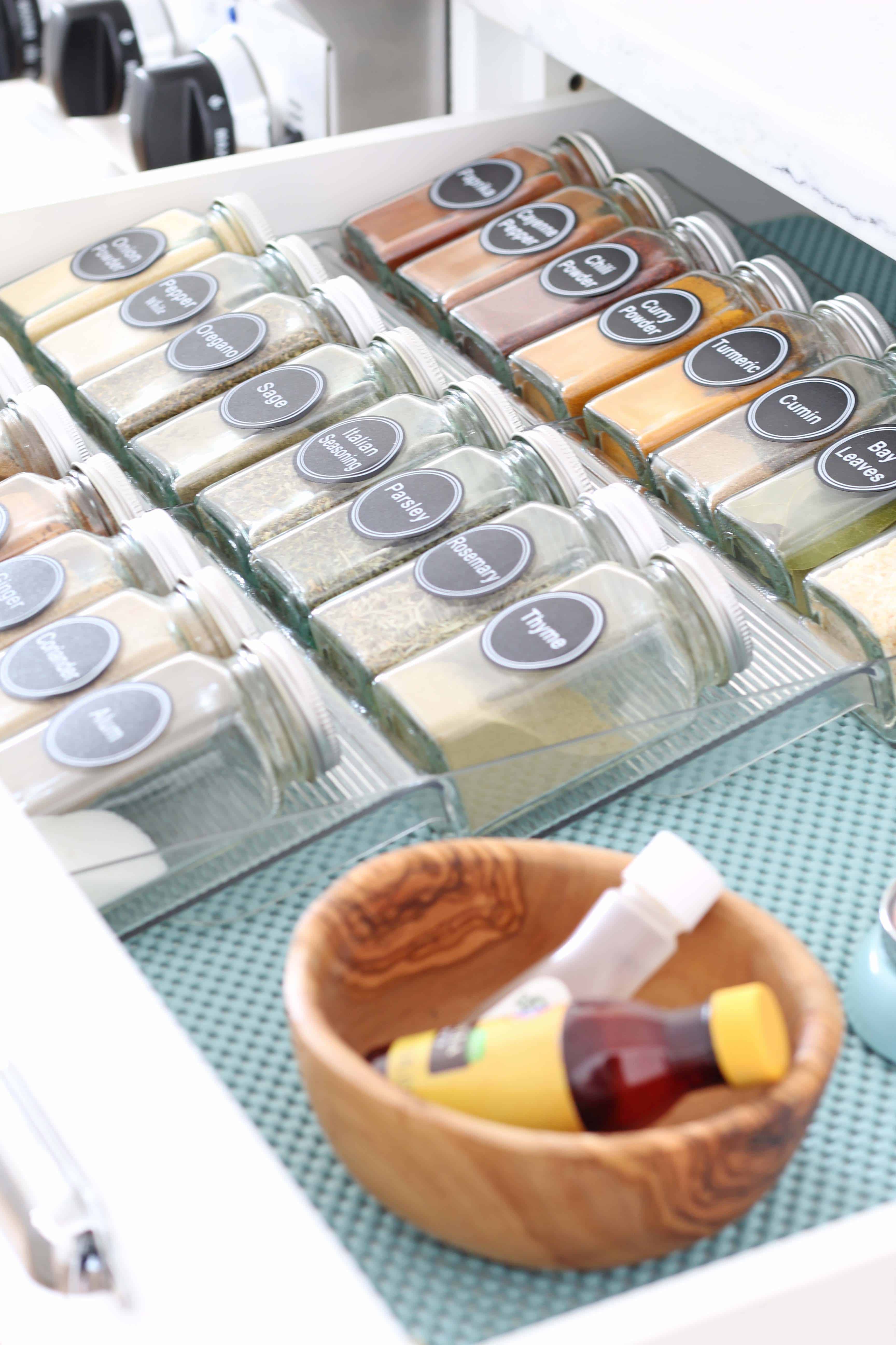glass spice bottles organized in a drawer with aqua drawer liner 