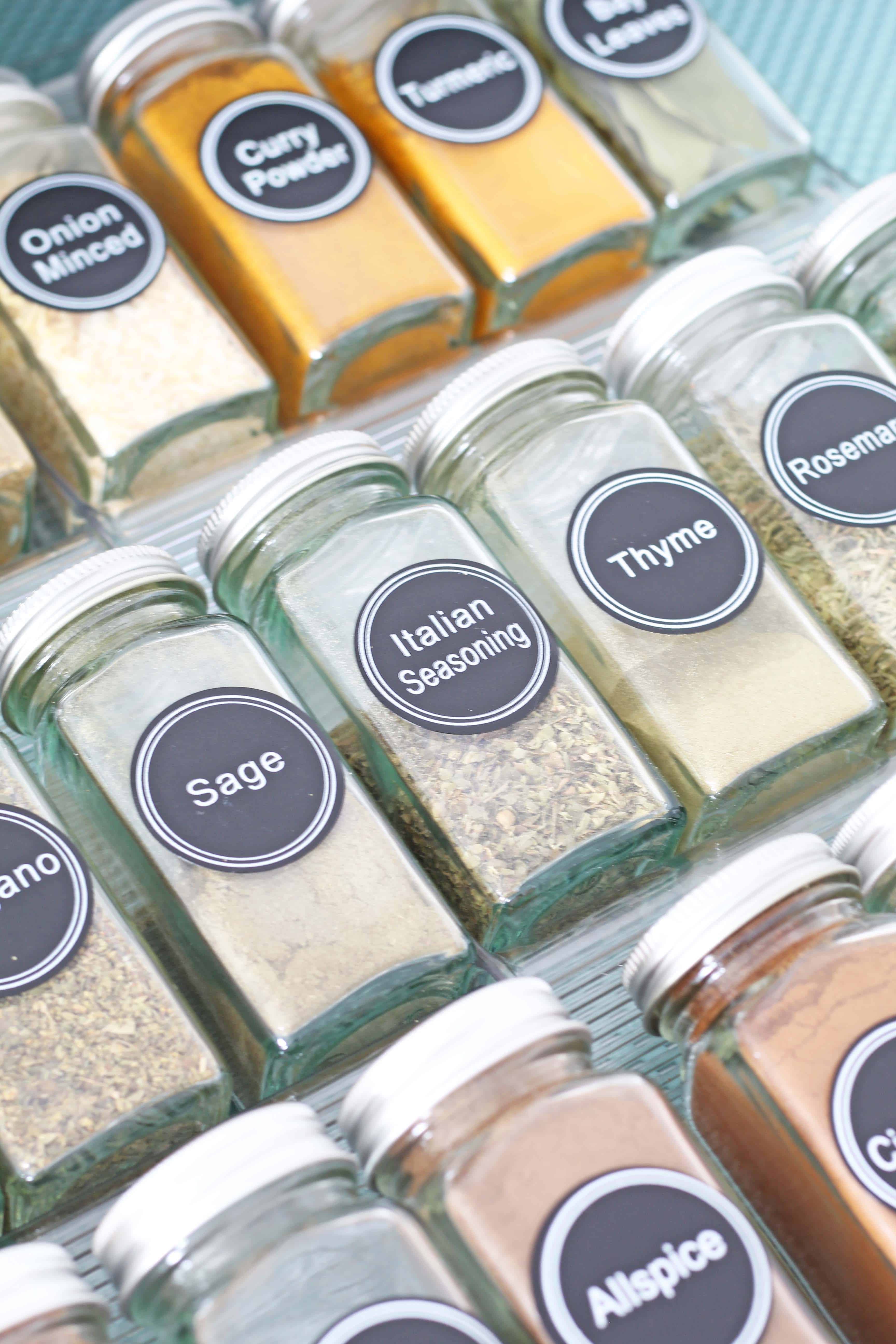 glass spice bottles organized in a drawer with aqua drawer liner 