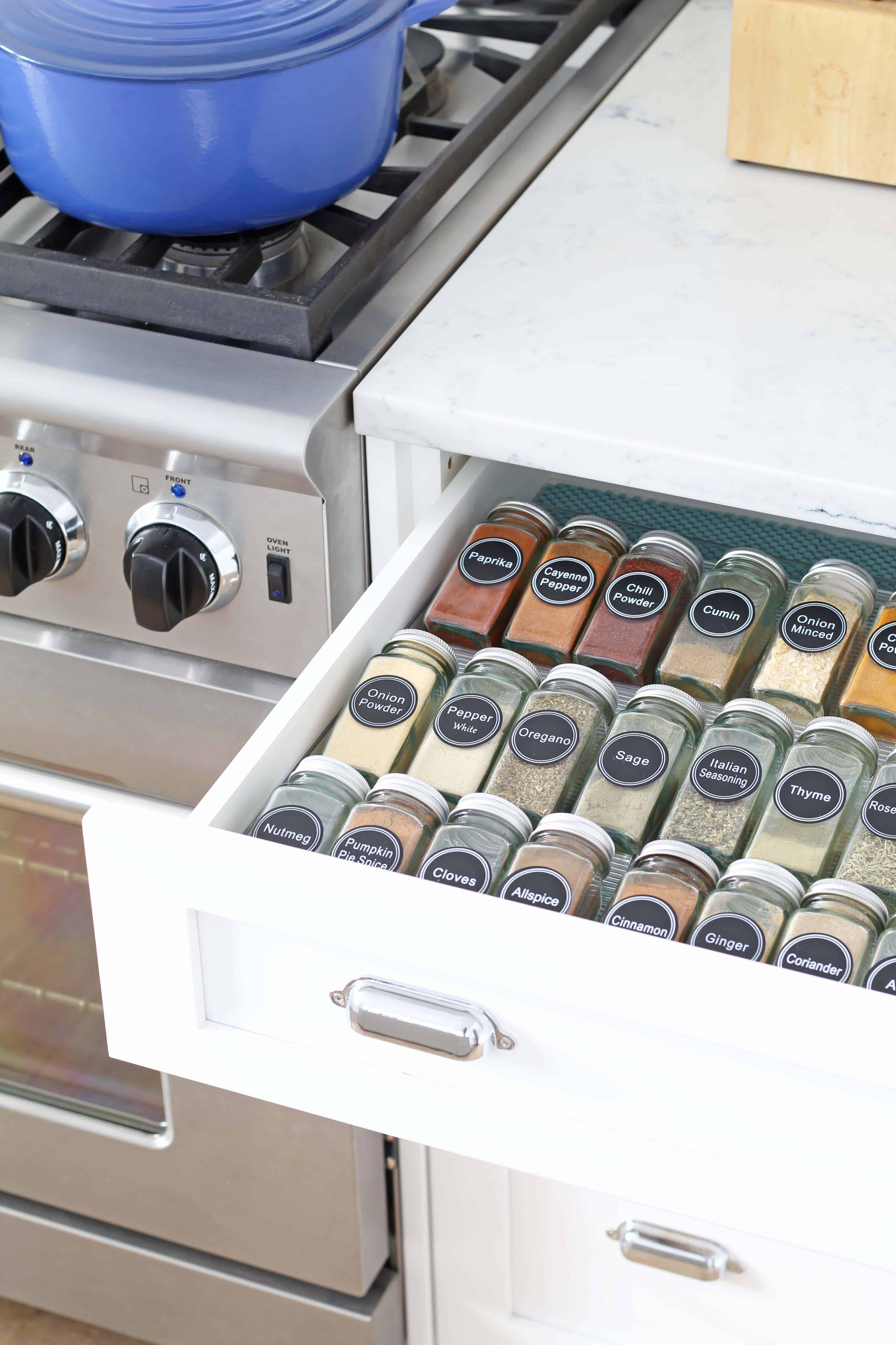 glass spice bottles organized in a drawer with aqua drawer liner 