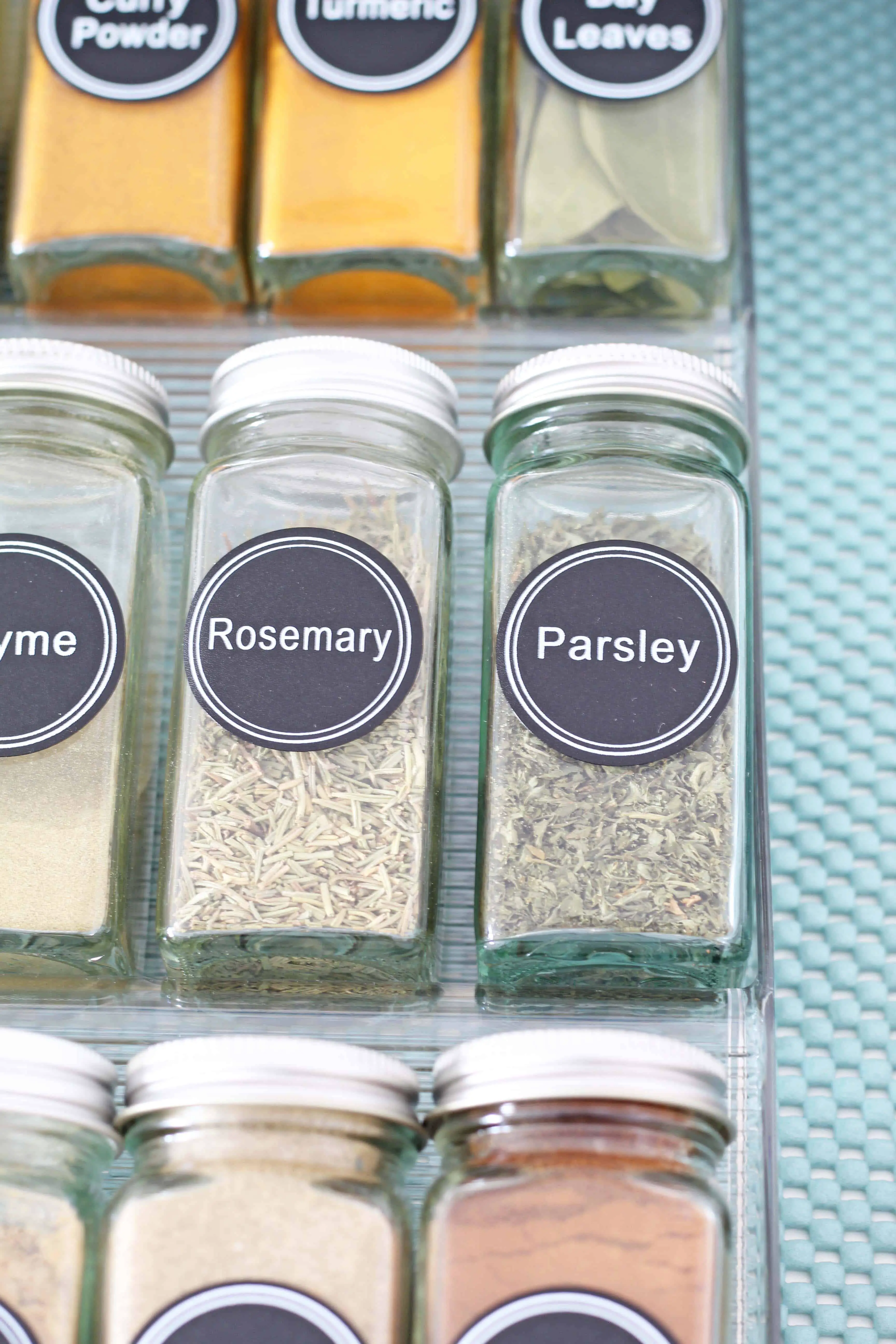 glass spice bottles organized in a drawer with aqua drawer liner 