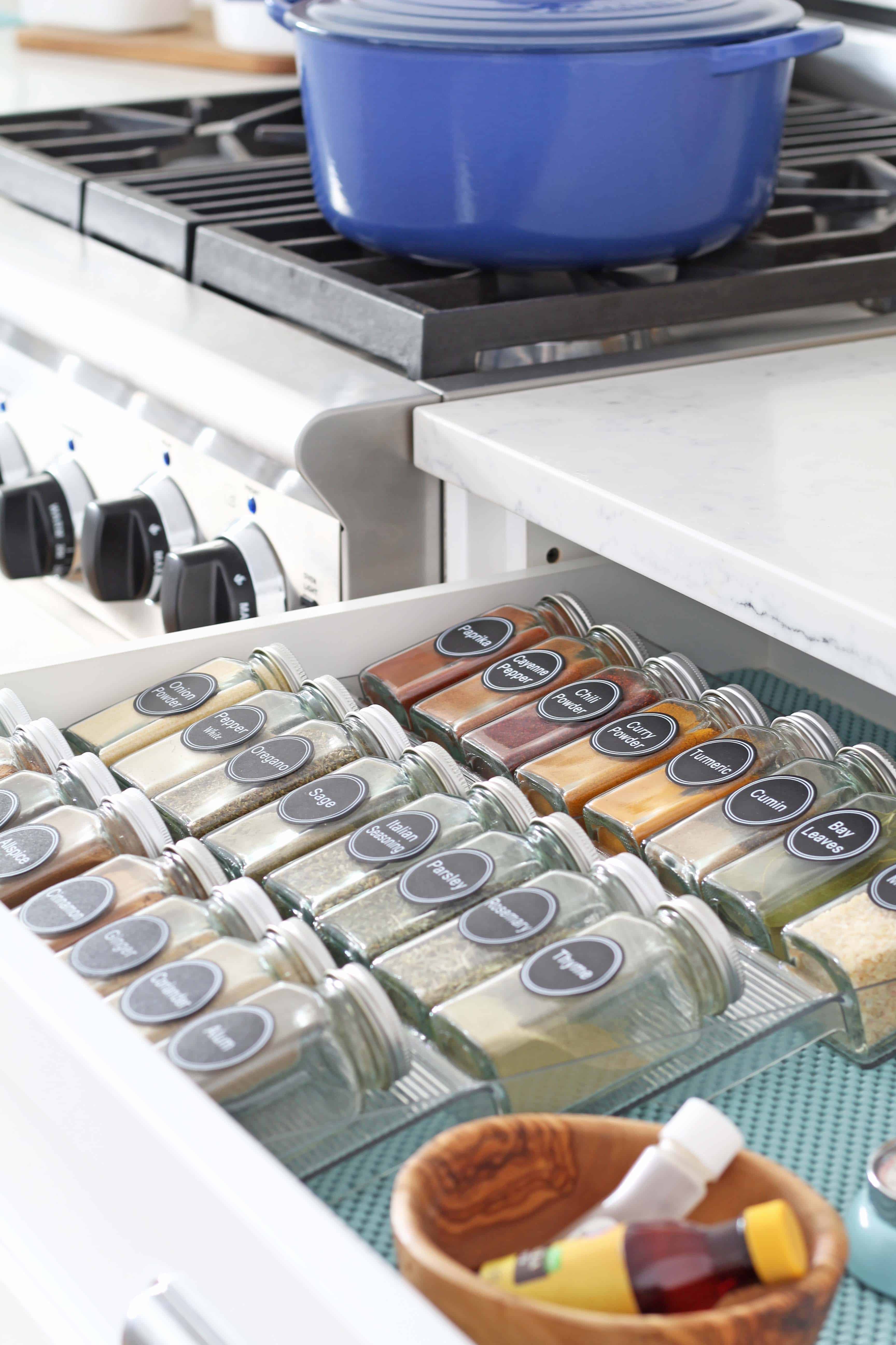 glass spice bottles organized in a drawer with aqua drawer liner 