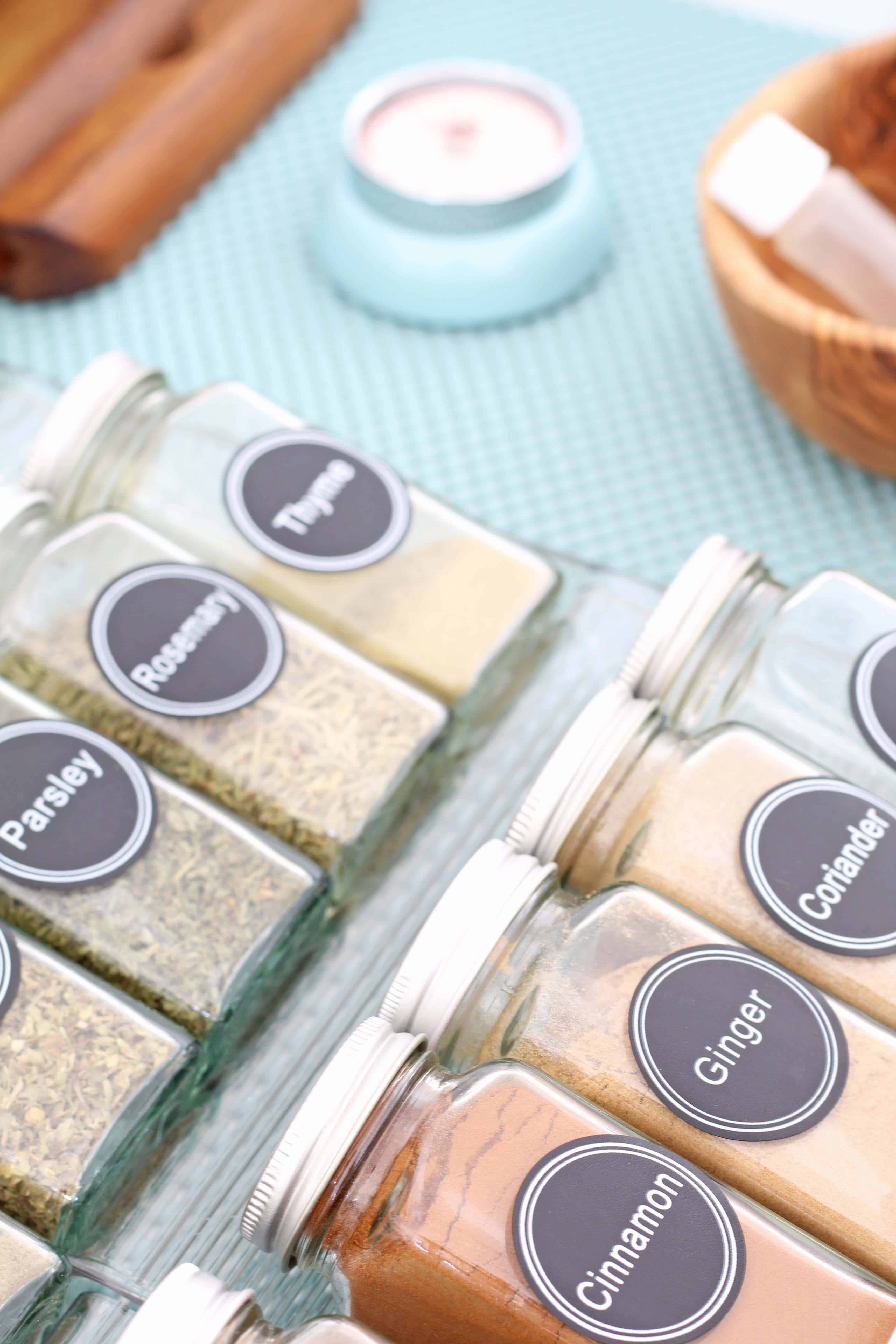 glass spice bottles organized in a drawer with aqua drawer liner 