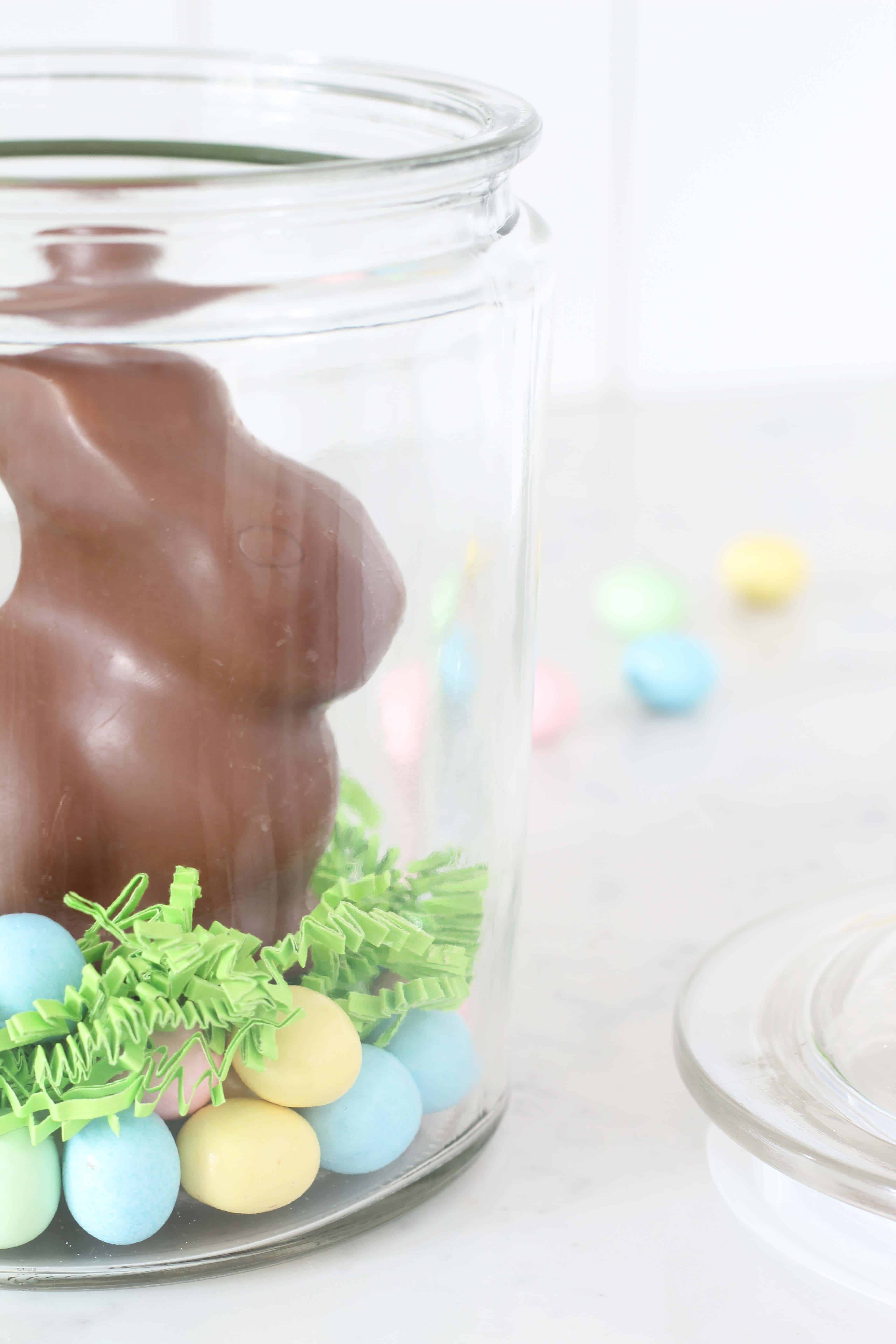 chocolate easter bunny in glass jar with pastel egg candy 