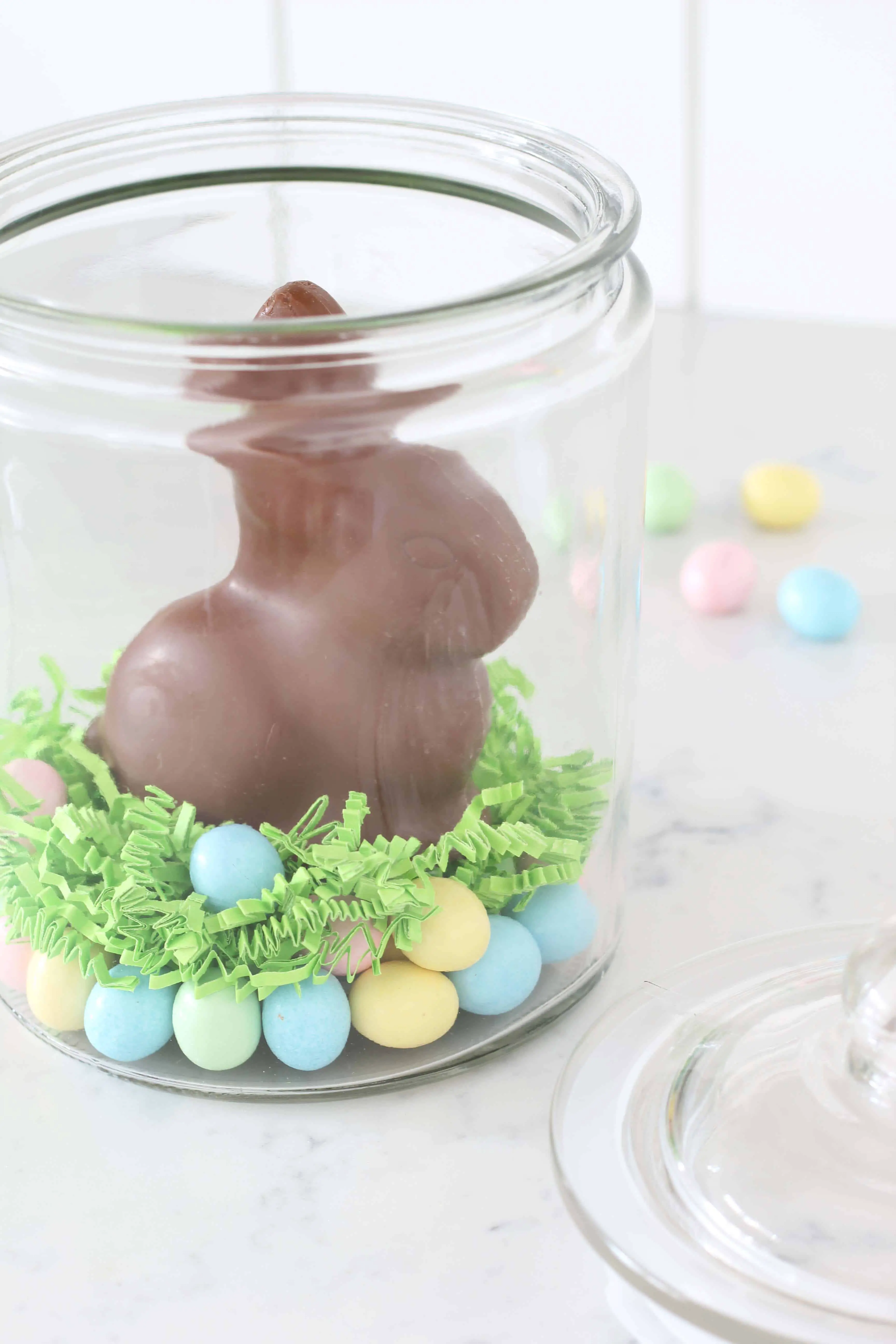 chocolate easter bunny in glass jar with pastel egg candy 