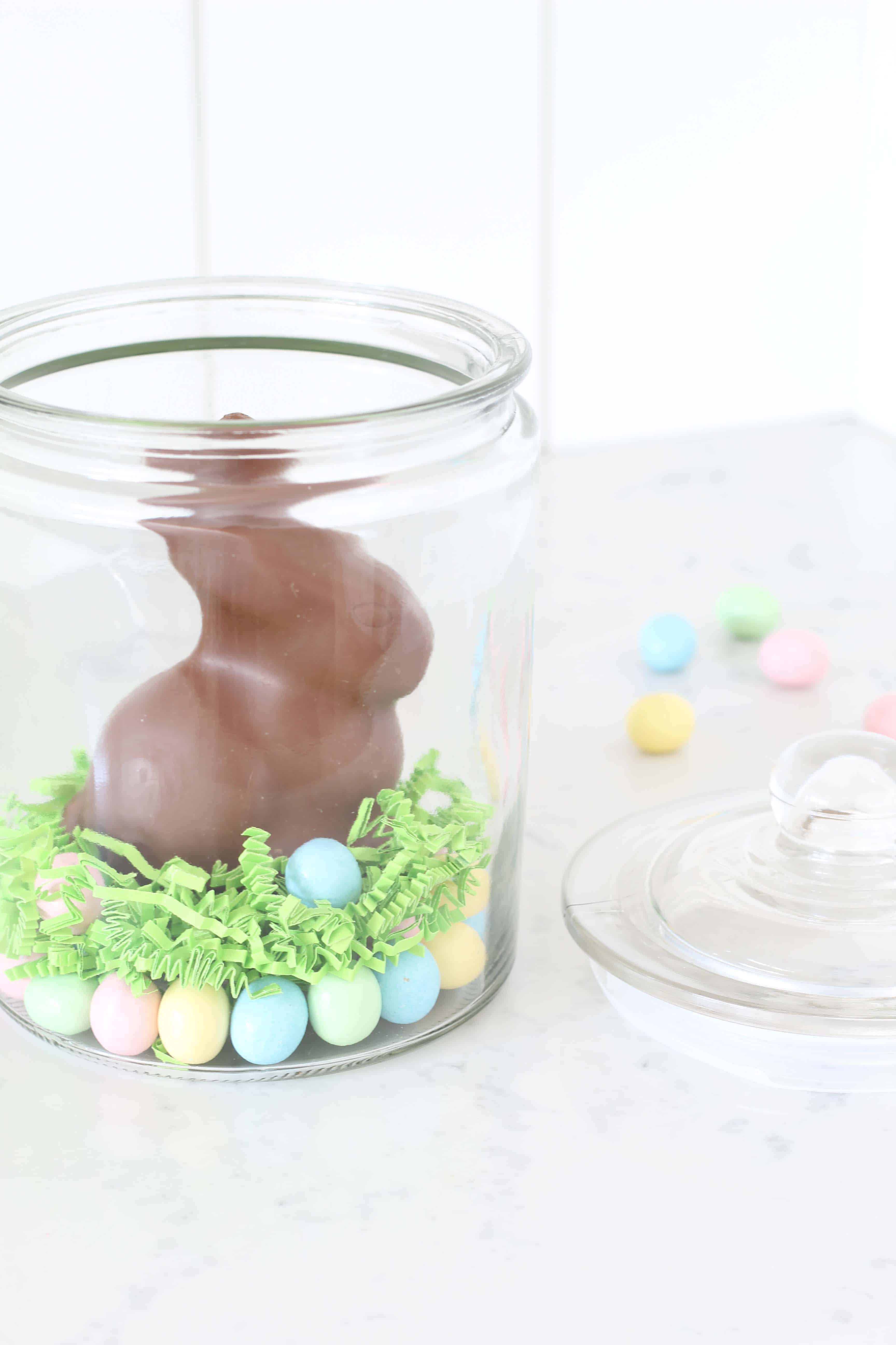 chocolate easter bunny in glass jar with pastel egg candy 