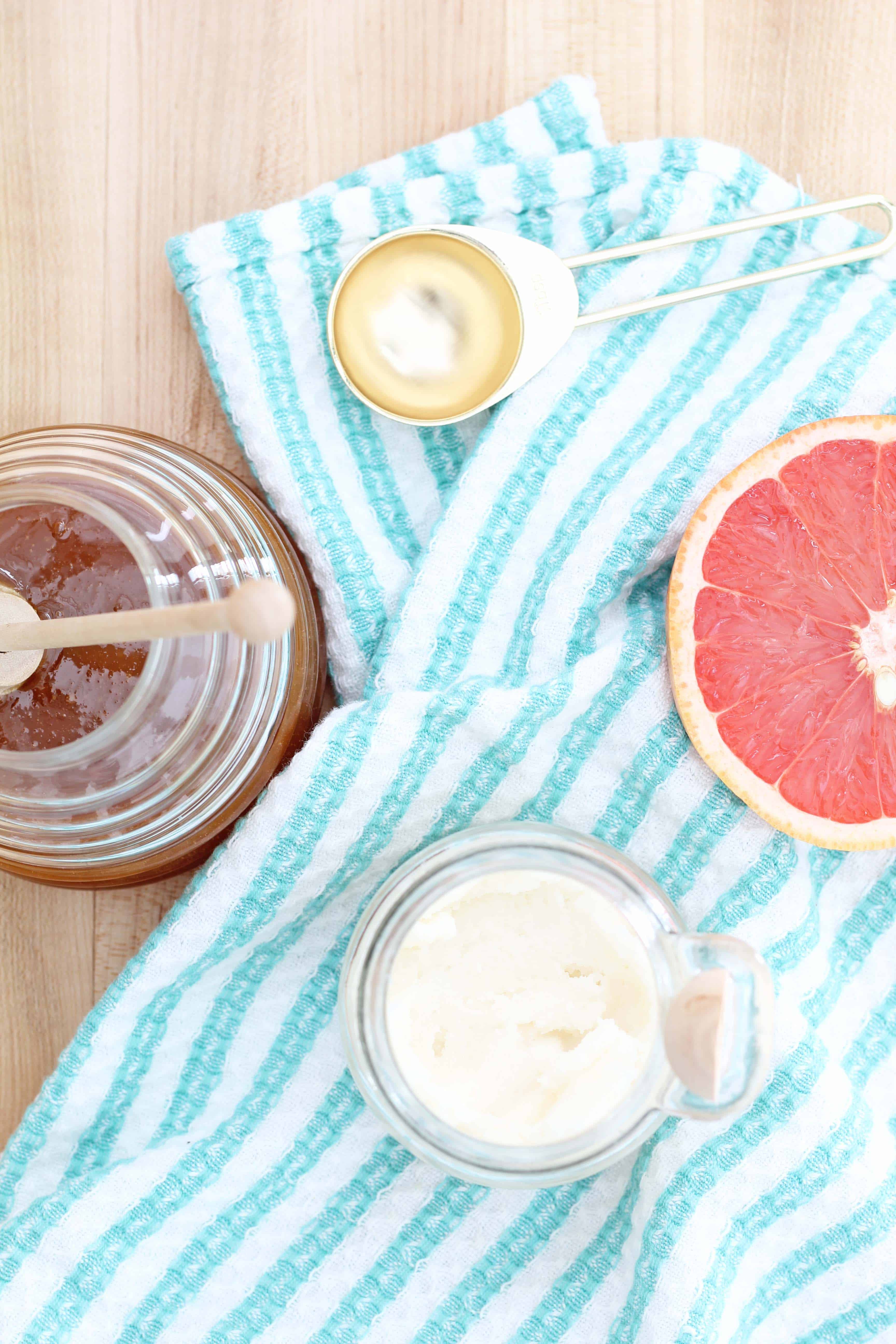 grapefruit, honey is glass beehive jar, gold measuring spoon, and apothecary jar