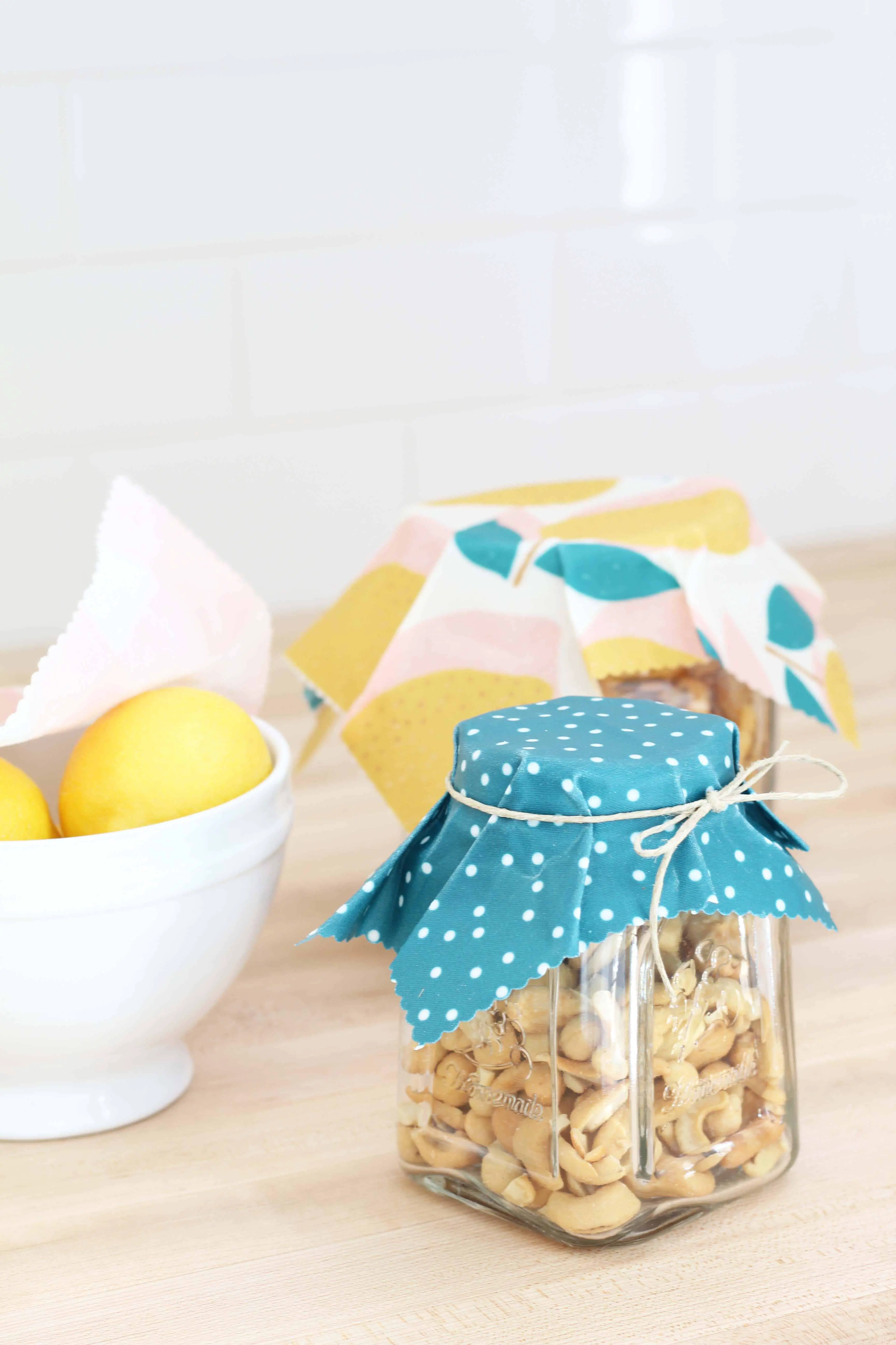 beeswax wrap in lemon print covering glass jars of food