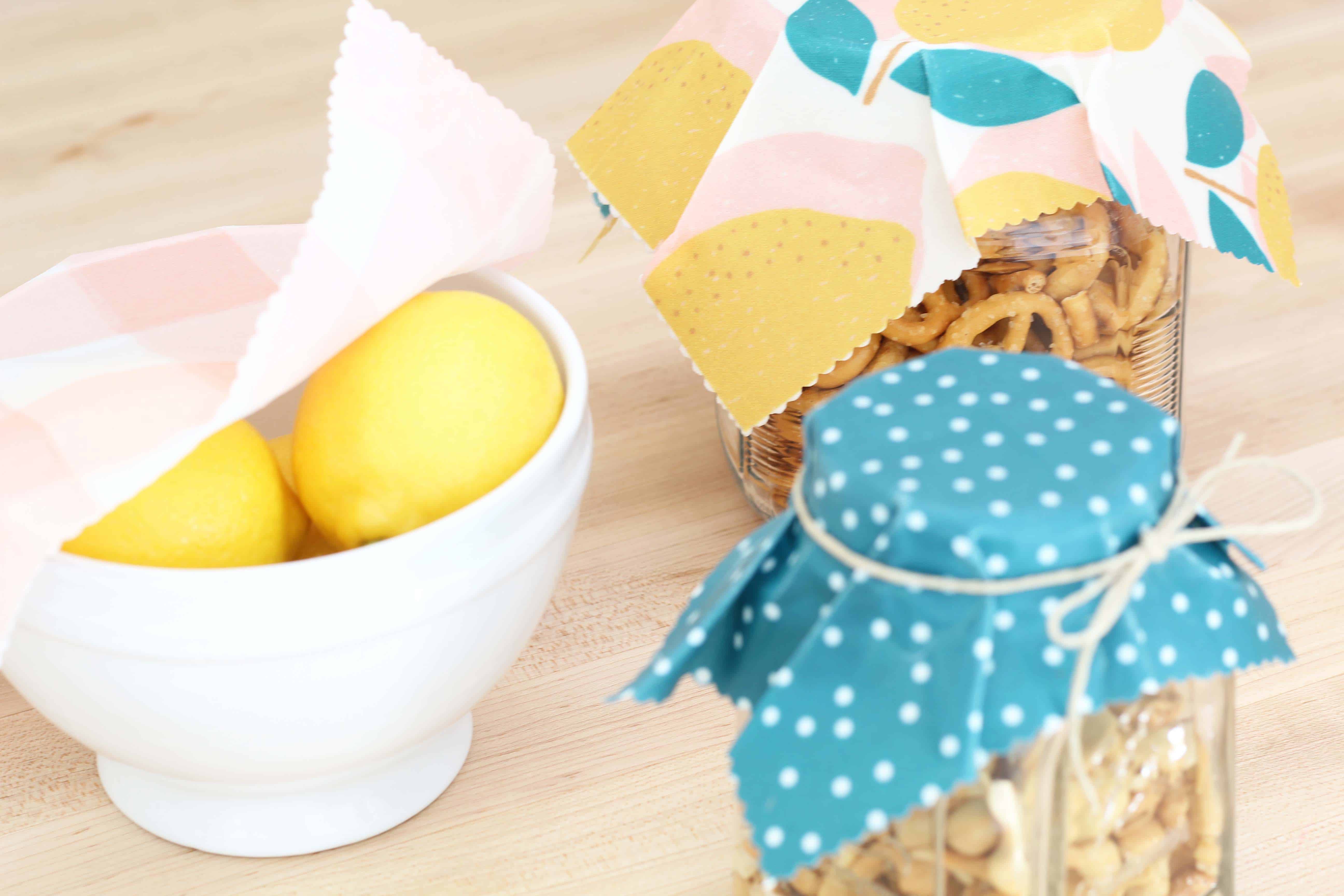 beeswax wrap in lemon print covering glass jars of food