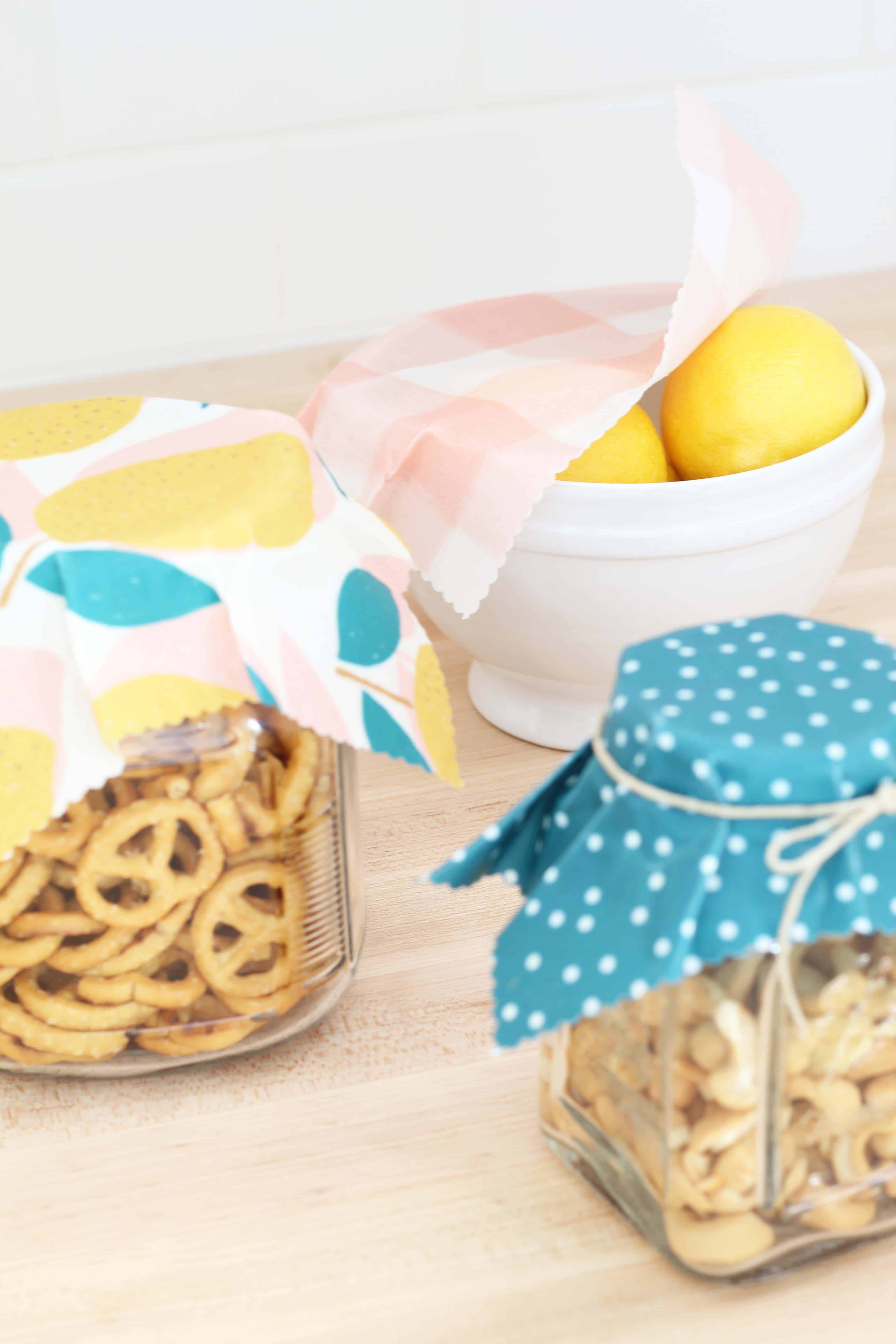 beeswax wrap in lemon print covering glass jars of food