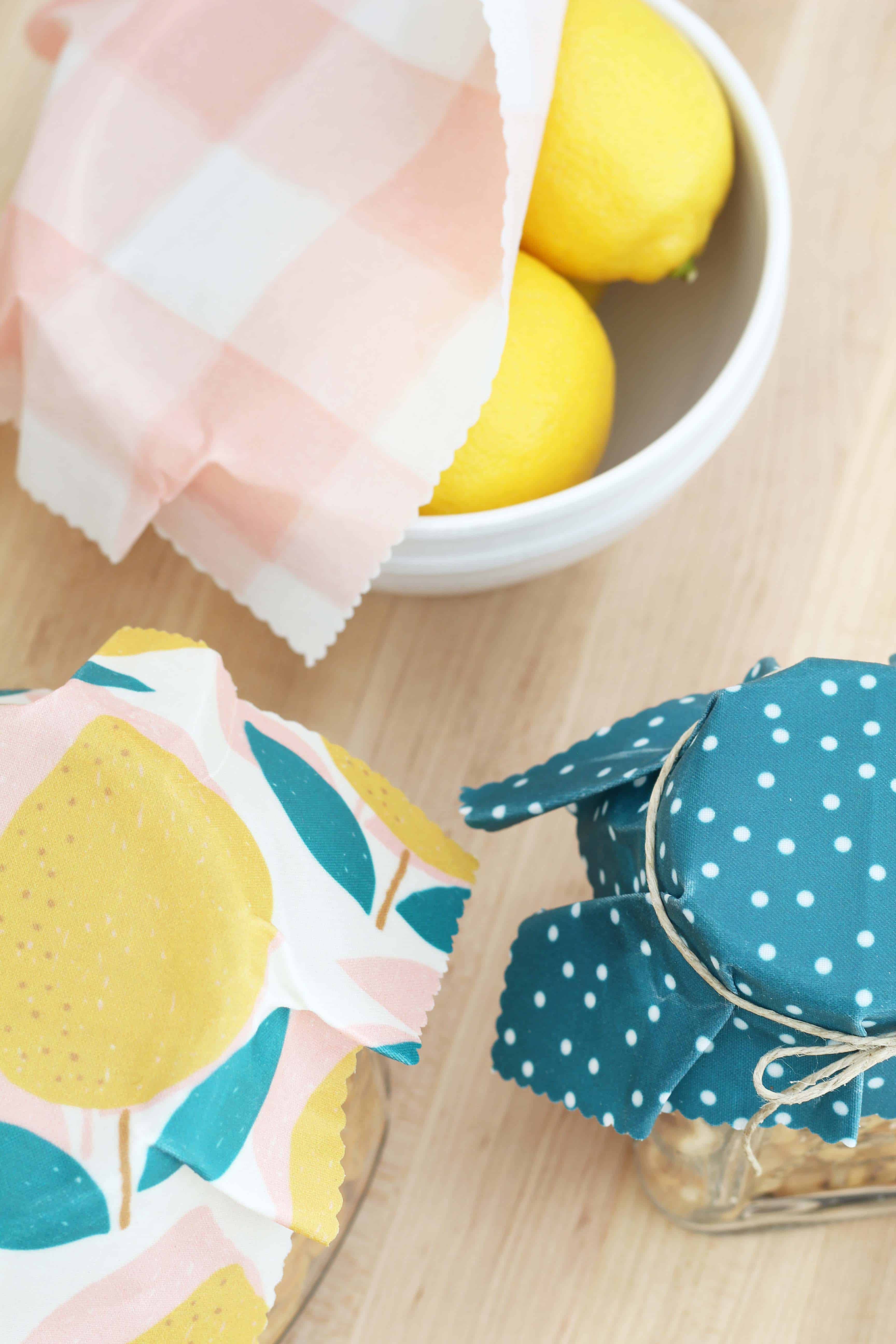 beeswax wrap in lemon print covering glass jars of food