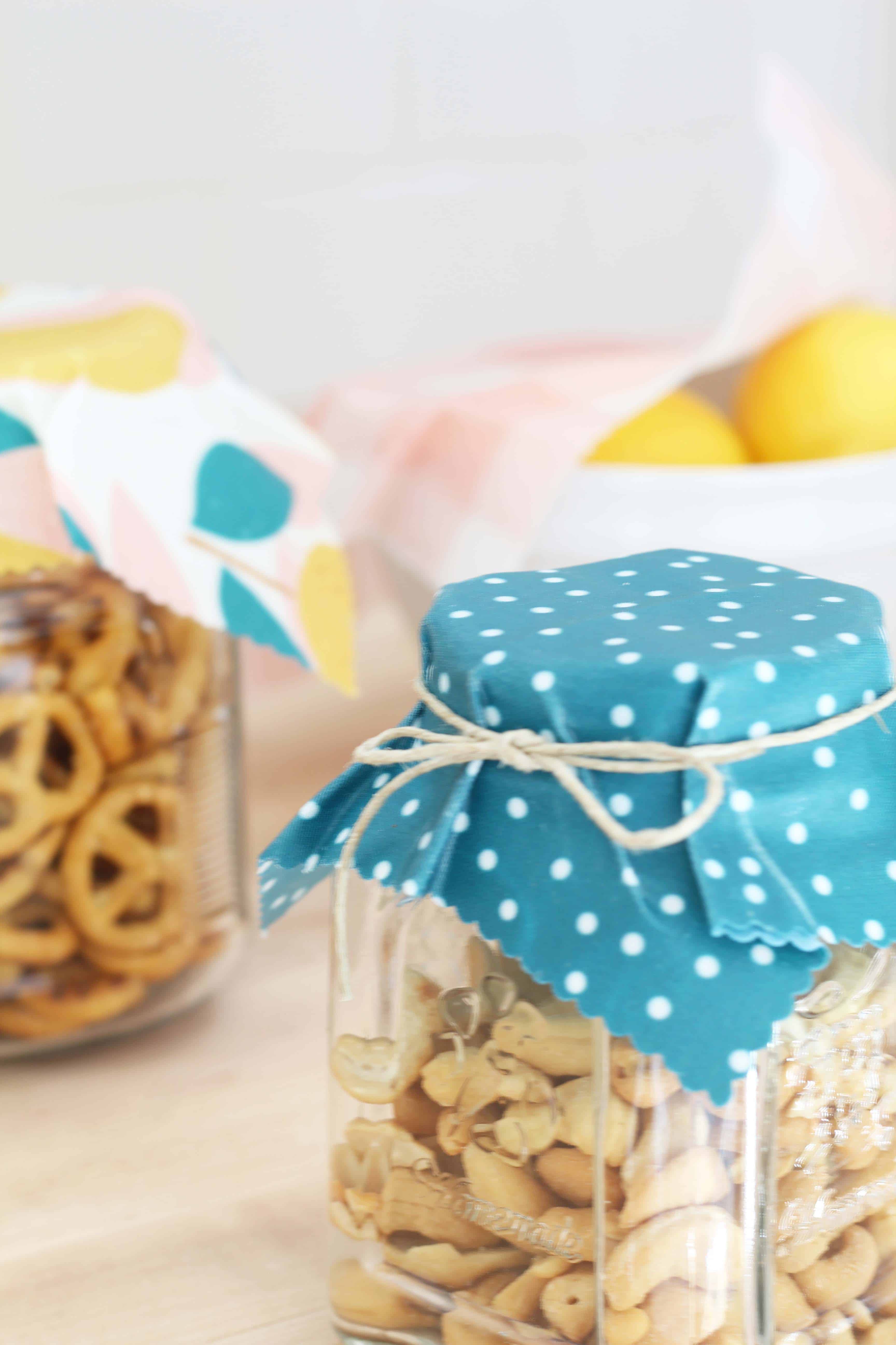 beeswax wrap in lemon print covering glass jars of food