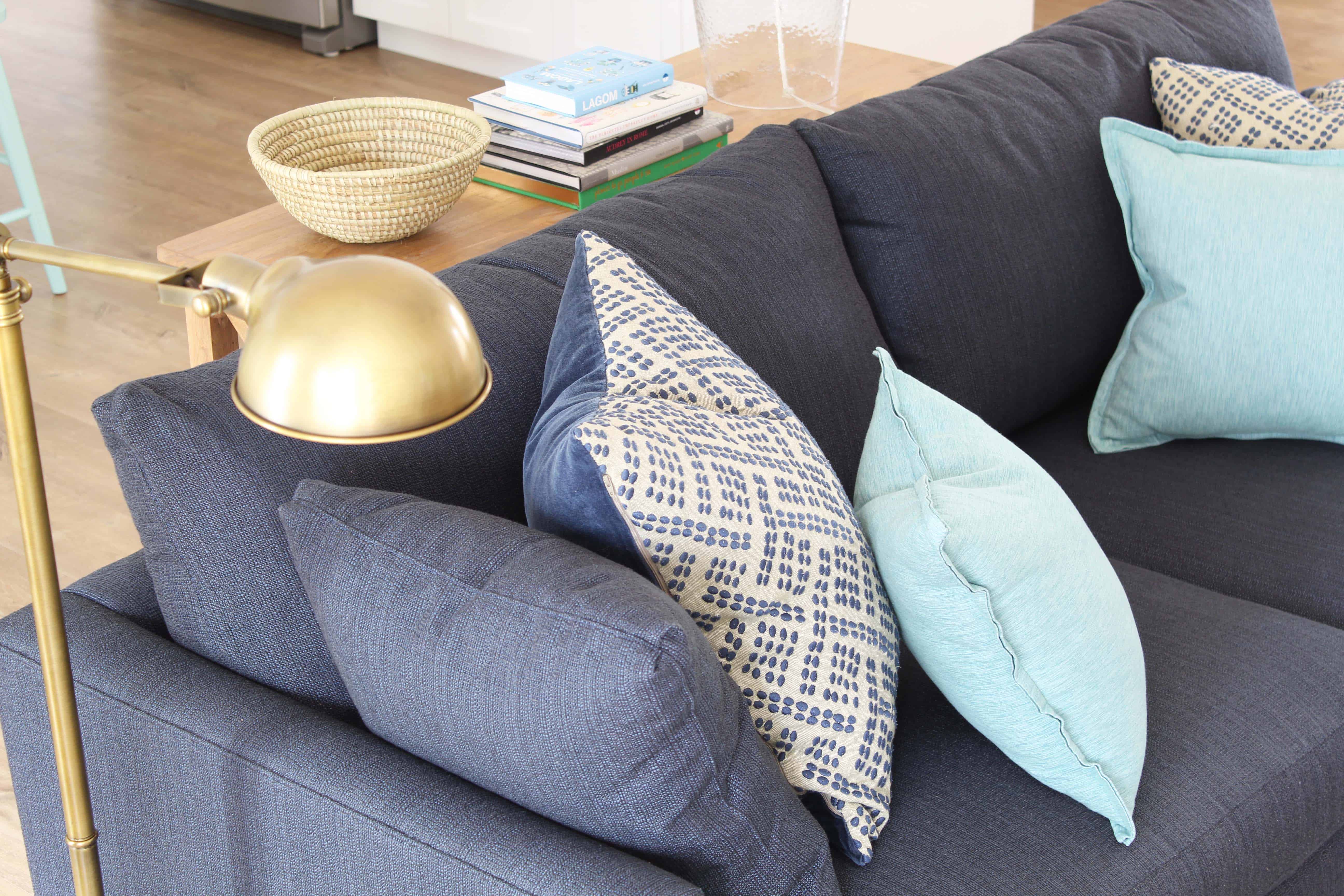 navy blue crate and barrel lounge II petite sofa, brass apothecary lamp, aqua throw pillows, and african woven basket 