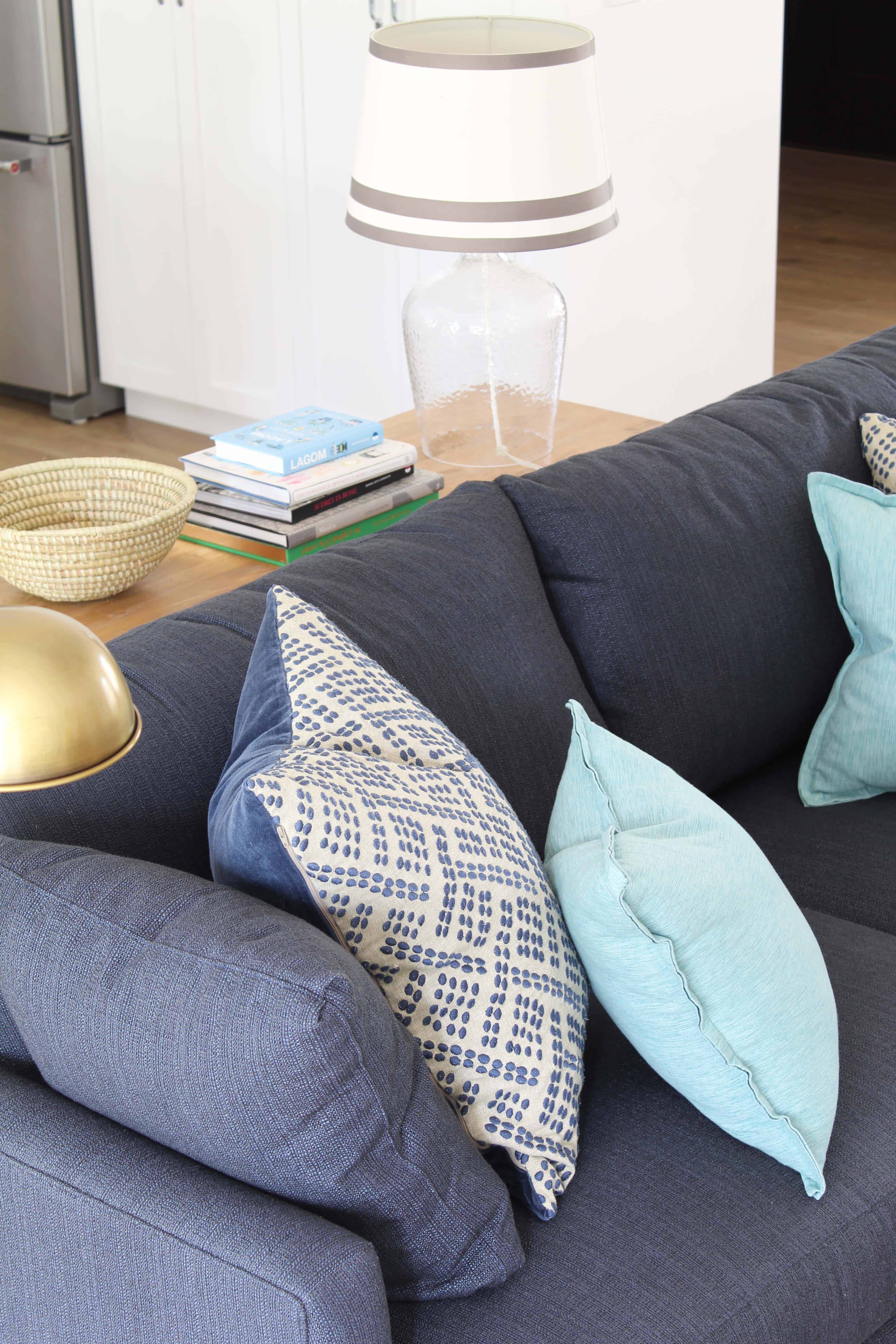 navy blue crate and barrel lounge II petite sofa, brass apothecary lamp, aqua throw pillows, and african woven basket 