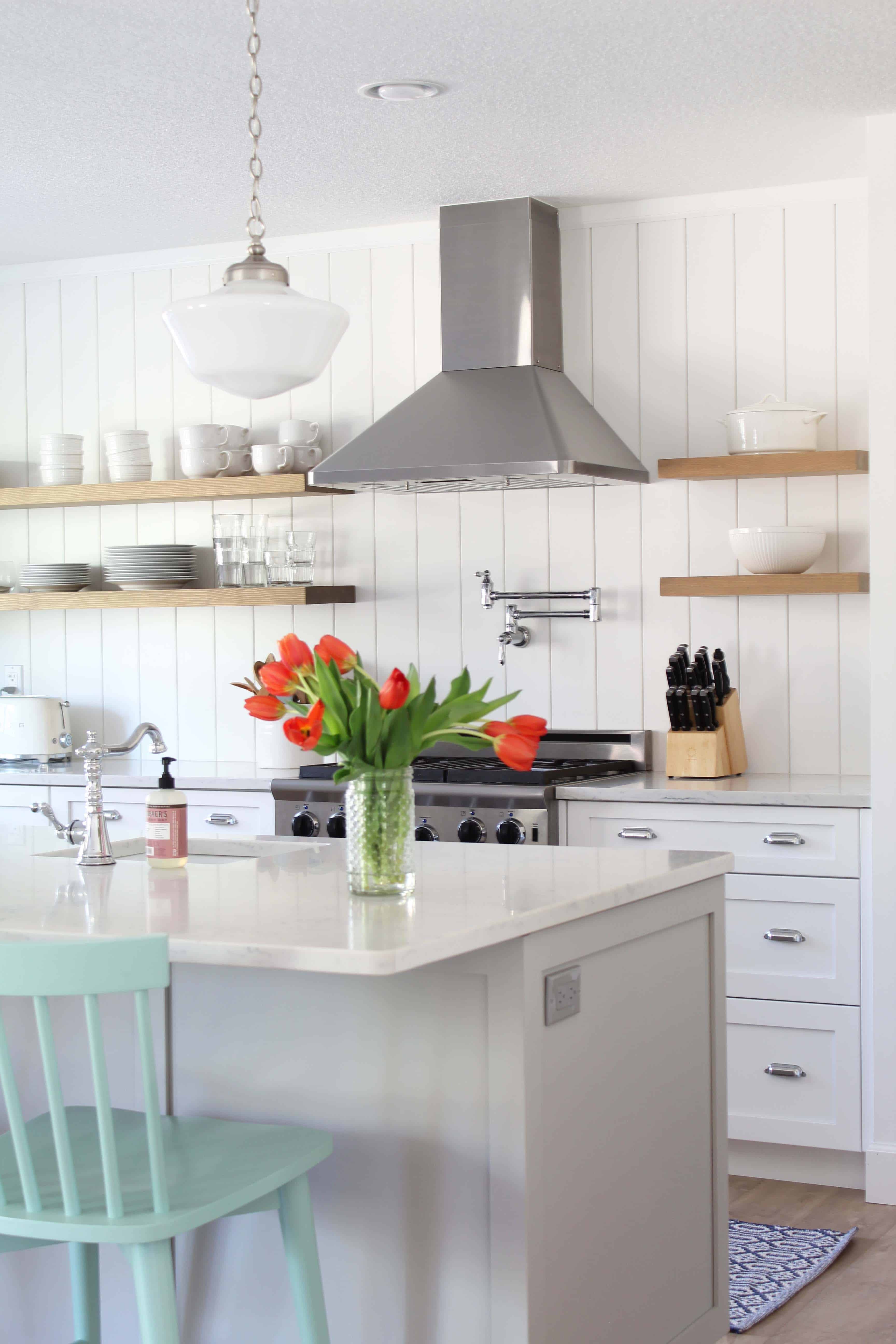 kitchen with light wood open shelves, vertical shiplap backsplash, vertical tongue and groove backsplash, kitchen with gray island and white cabinets 