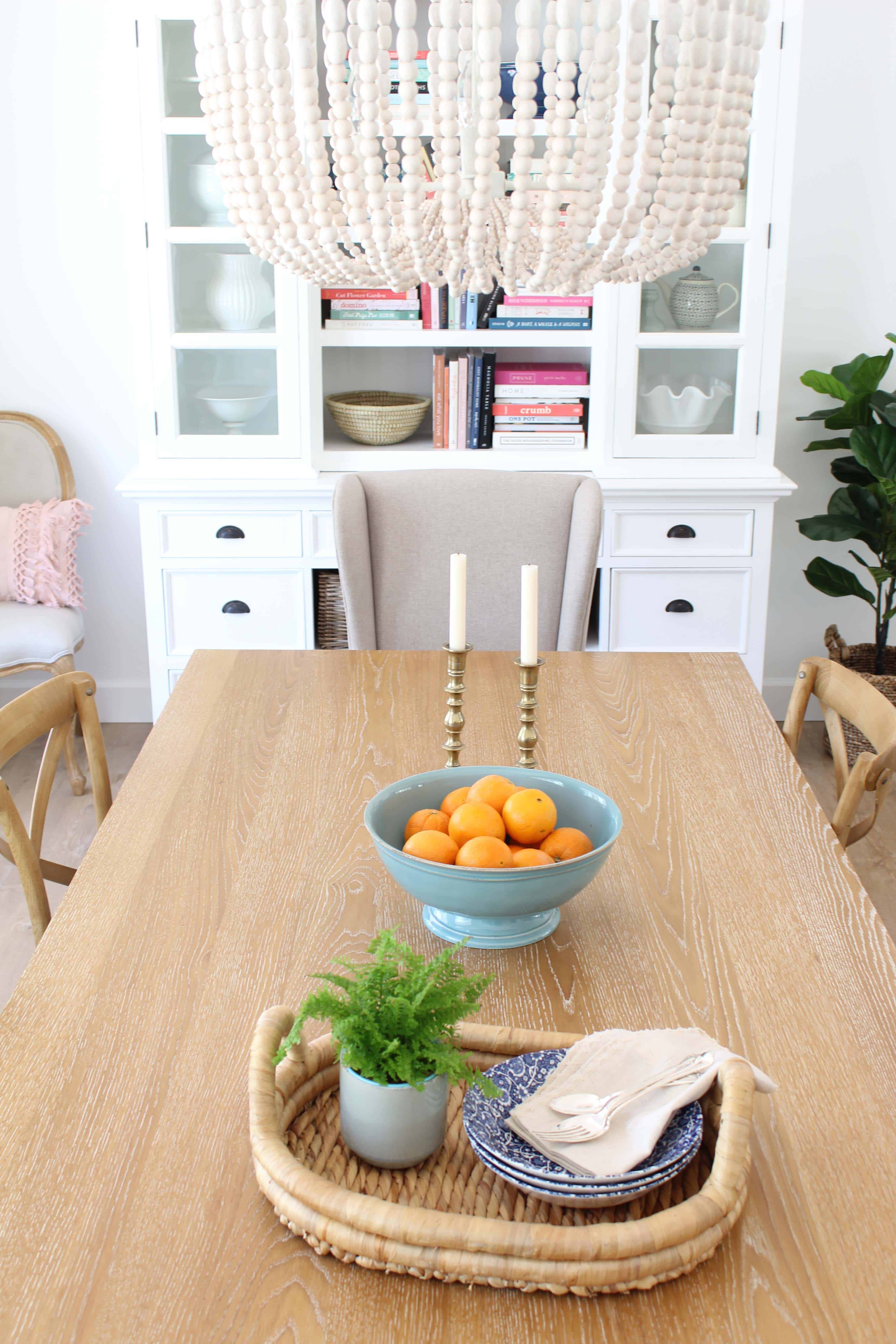 pier 1 dining room table, farmhouse bistro chairs, world market beaded chandelier, brass candlesticks, pottery barn aqua bowl with oranges