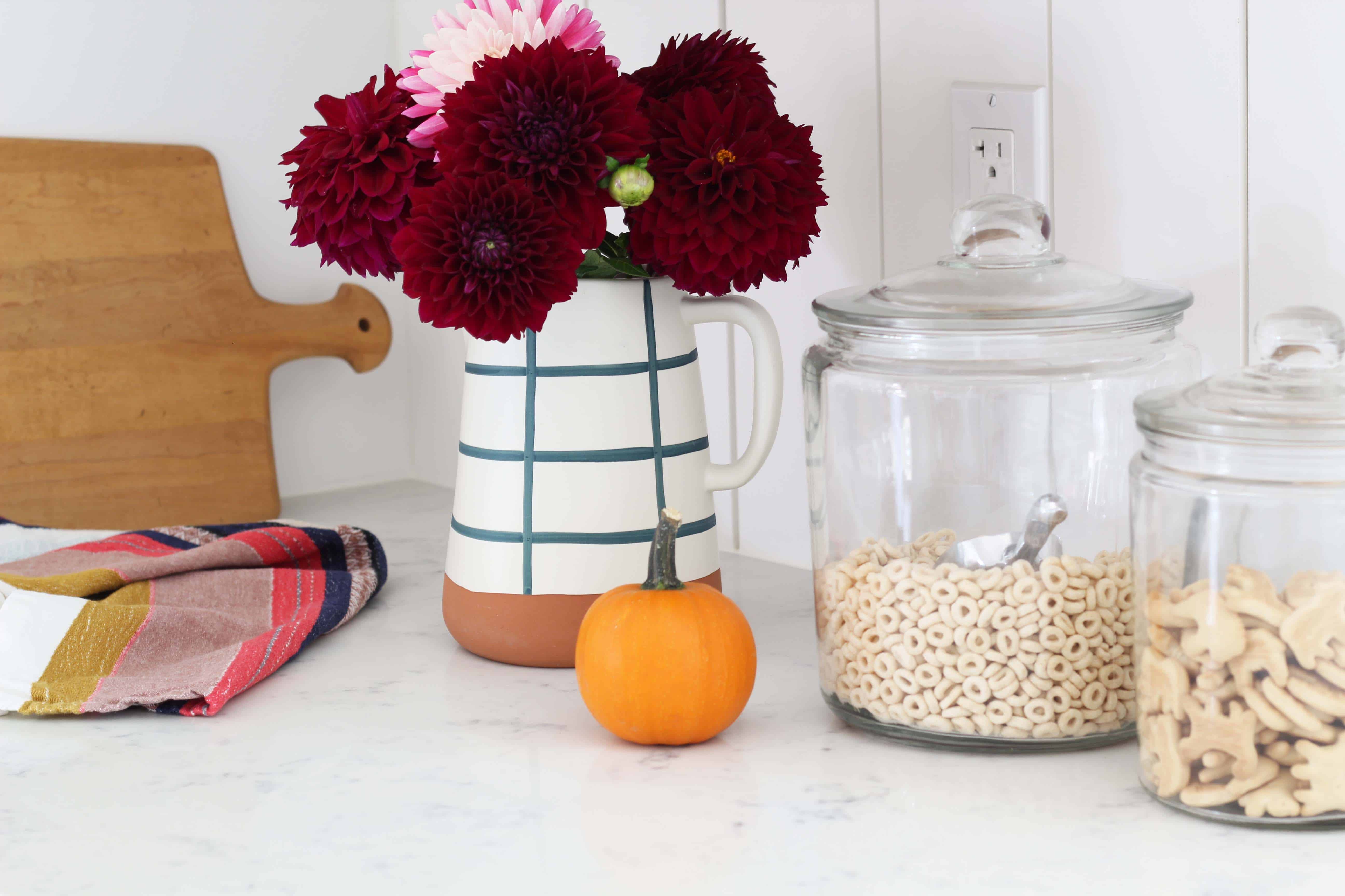 fall mums in threshold magnolia home pitcher, mini pumpkin decor, cheerios in glass canister 