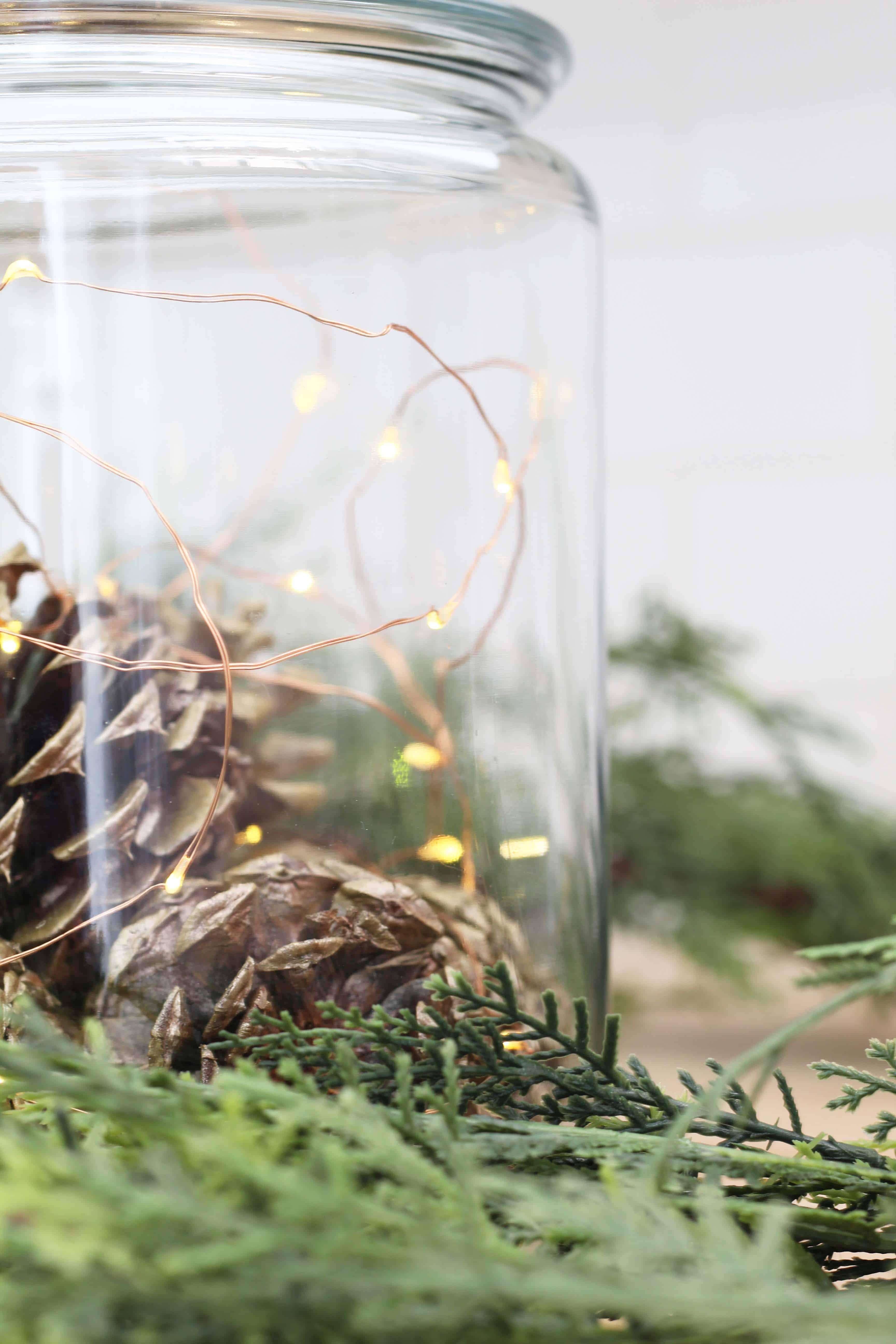 gold pinecones in glass canister with fairy lights and faux pine garland