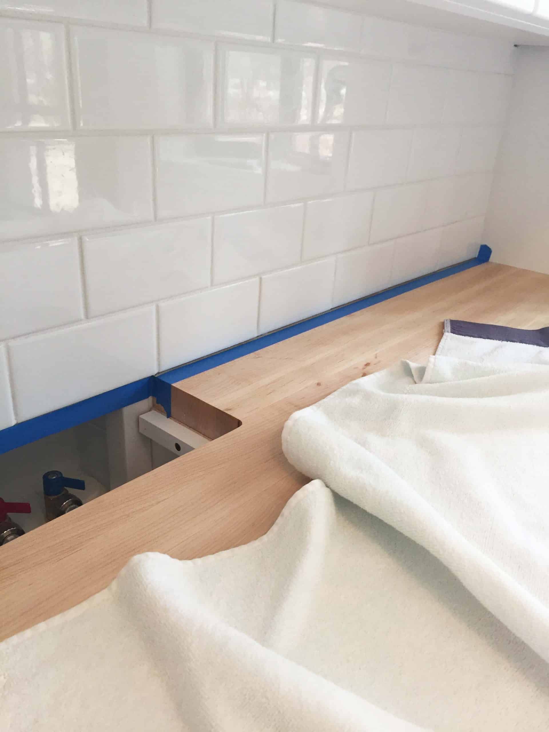 white subway tile backsplash in laundry room with butcher block countertops