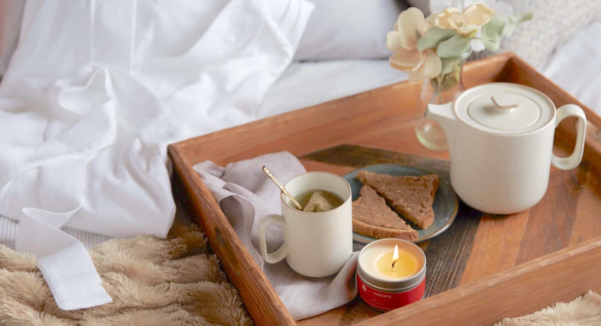 wood tray with tea and toast and candle, breakfast in bed, hygge style, 