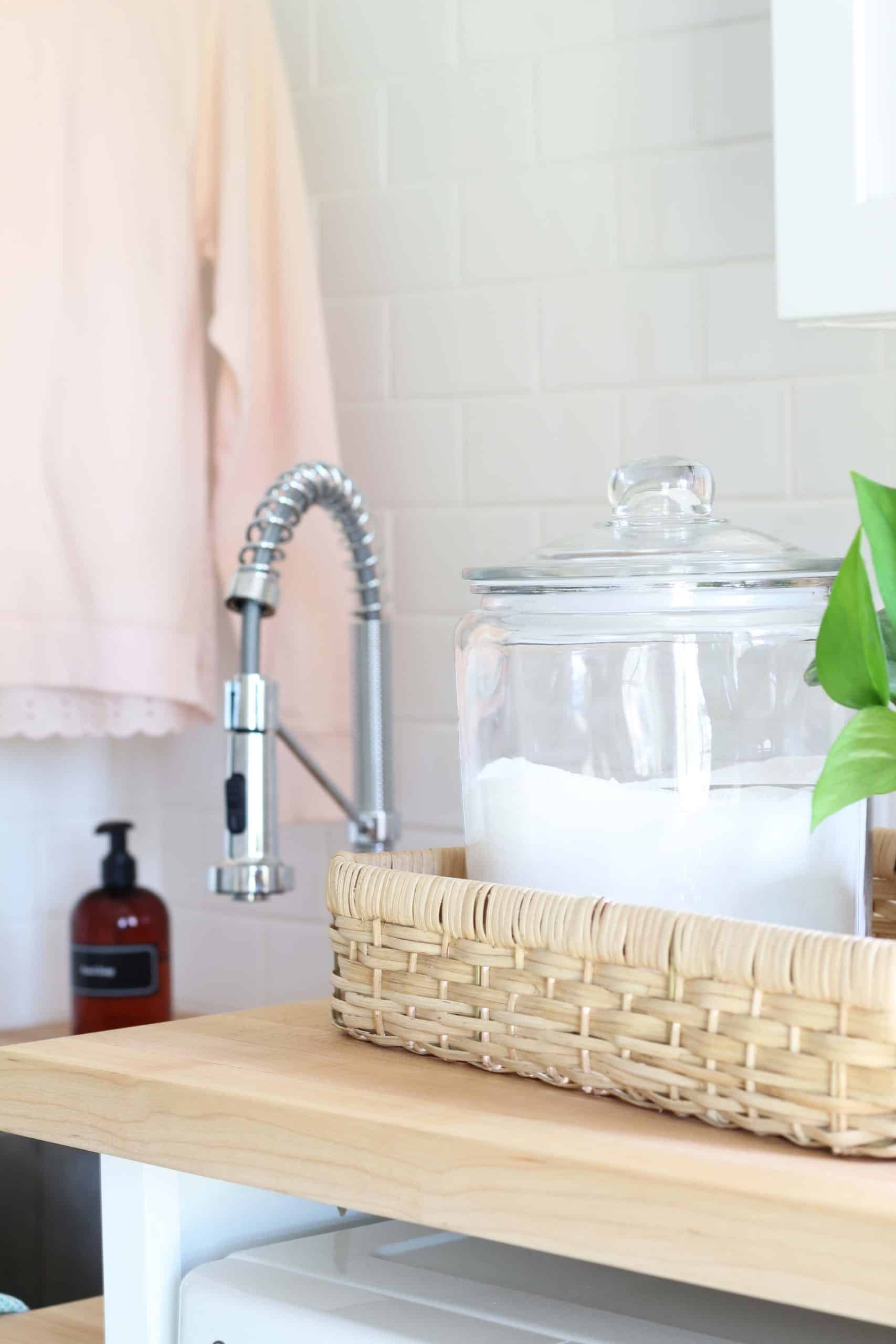 glass canister with laundry soap, maple butcher block countertops, white subway tile backsplash in laundry room, farmhouse style laundry room makeover