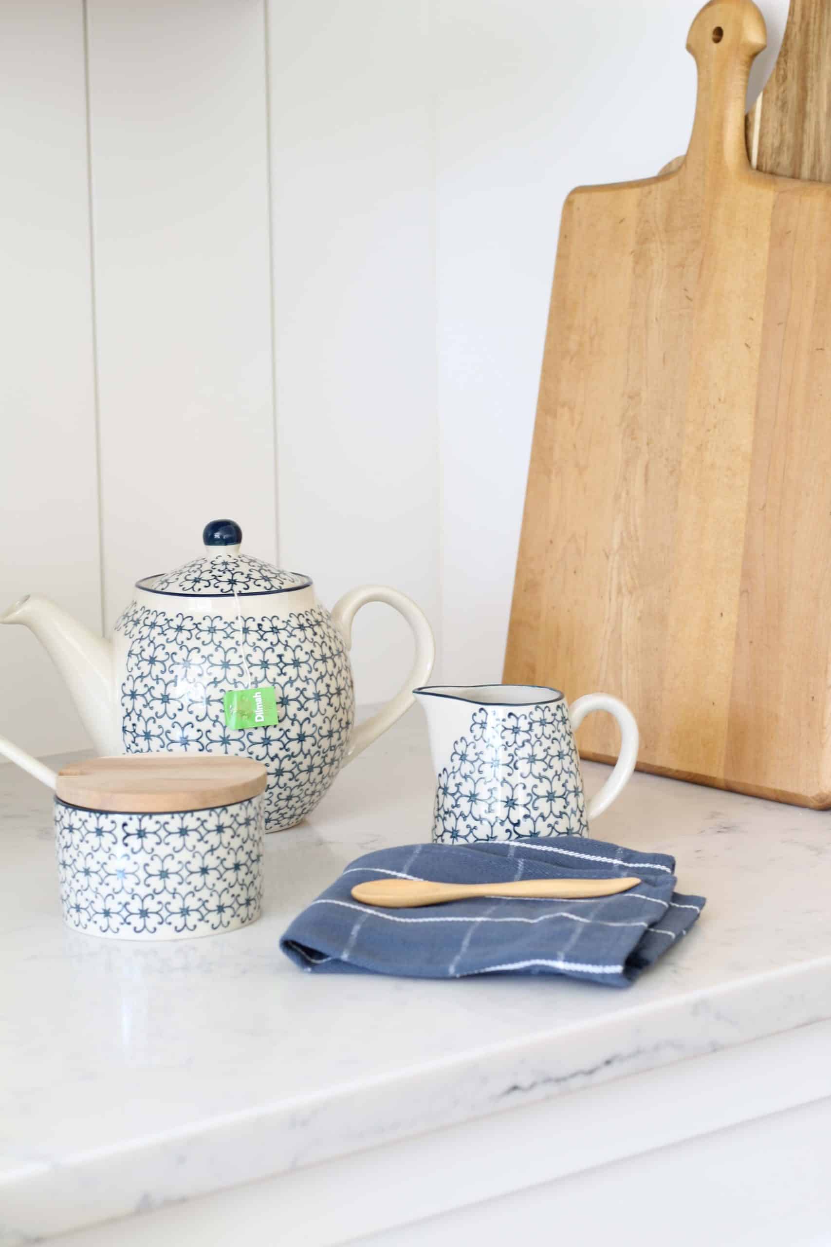 blue and white teapot, blue and white sugar bowl, blue and white creamer, natural wood breadboard, vertical shiplap kitchen backsplash, magnolia home wood spoons