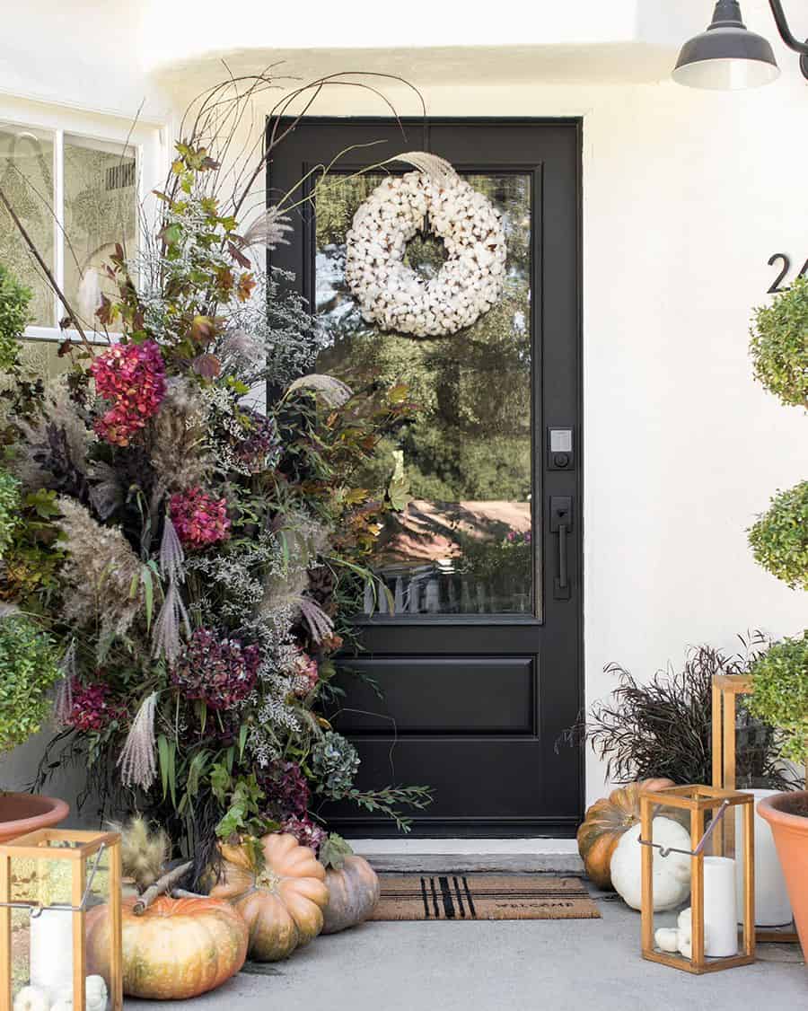 front porch with pumpkins, wood lanterns, and cotton wreath