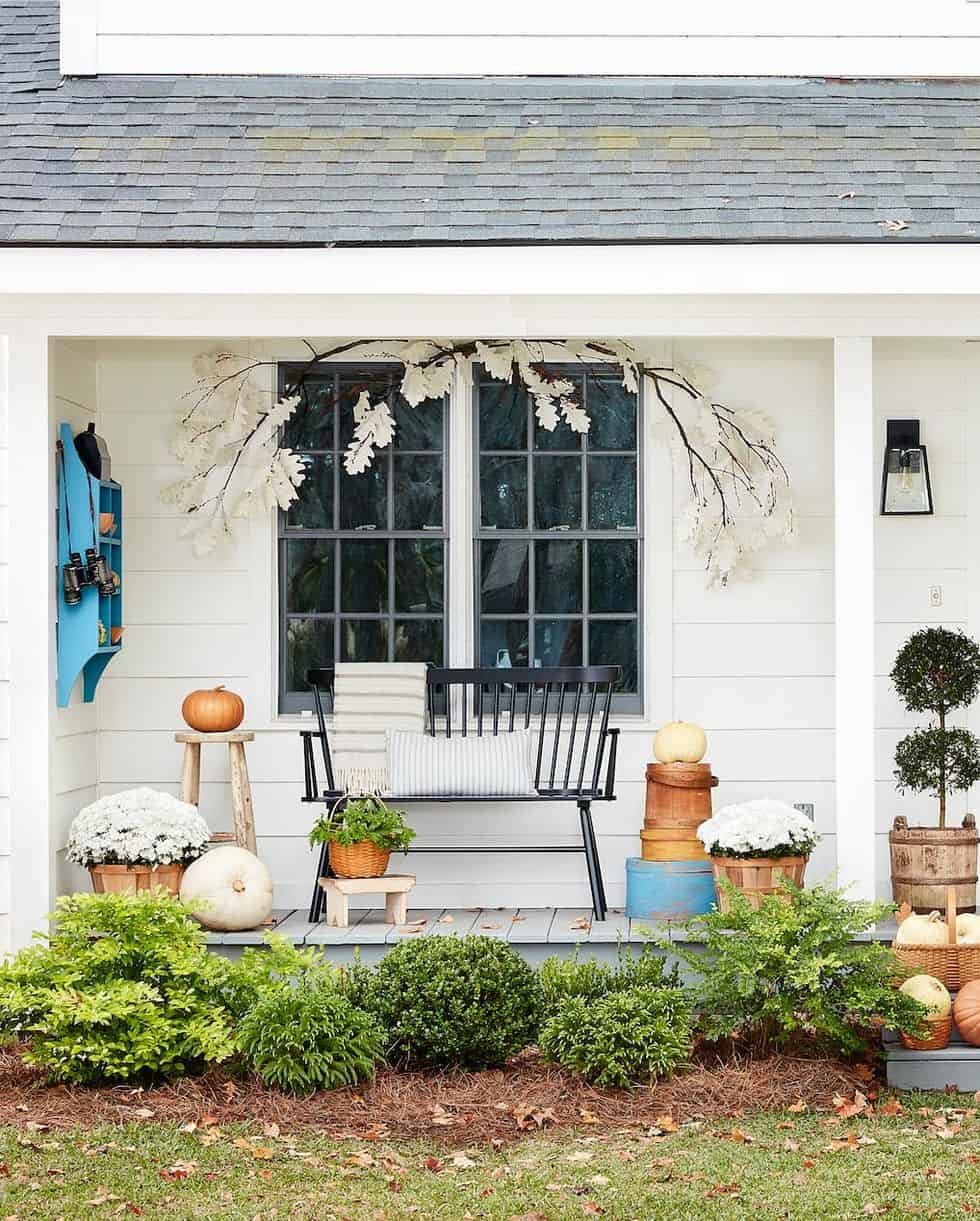 white farmhouse with pumpkins and mums on front porch