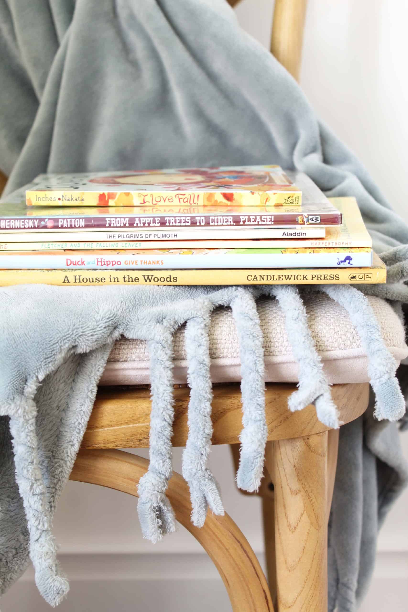 teal blanket with fall children's books on a farmhouse style chair 