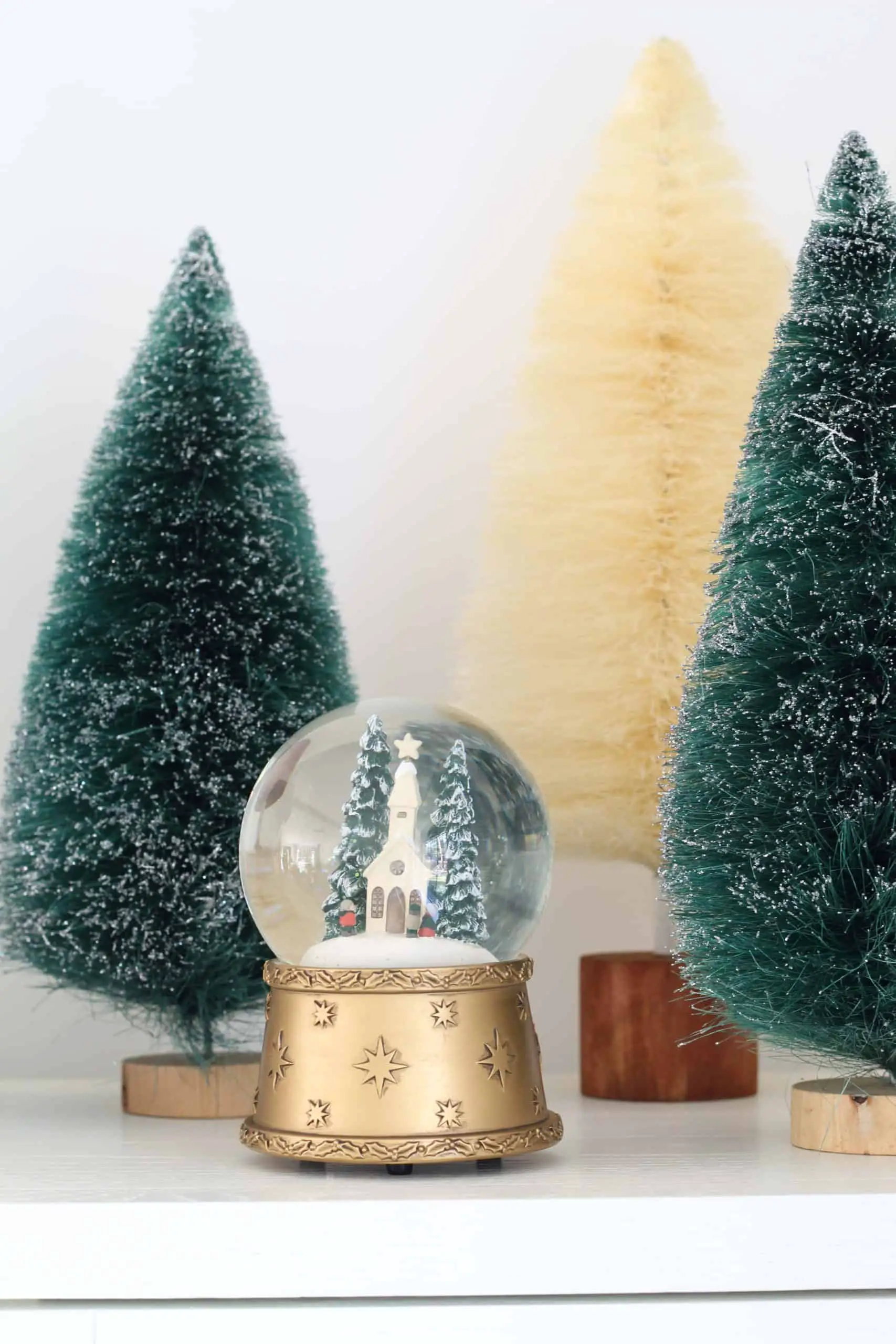 bottle brush trees and snow globe with church in it