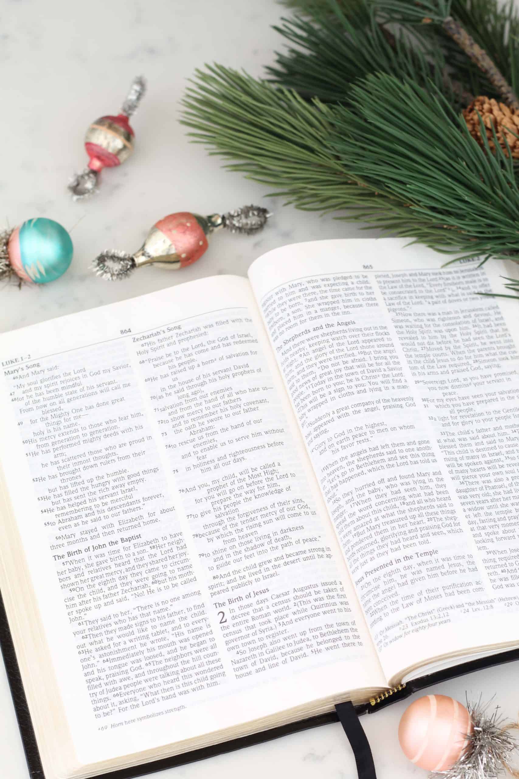 open bible with christmas ornaments and pine branch