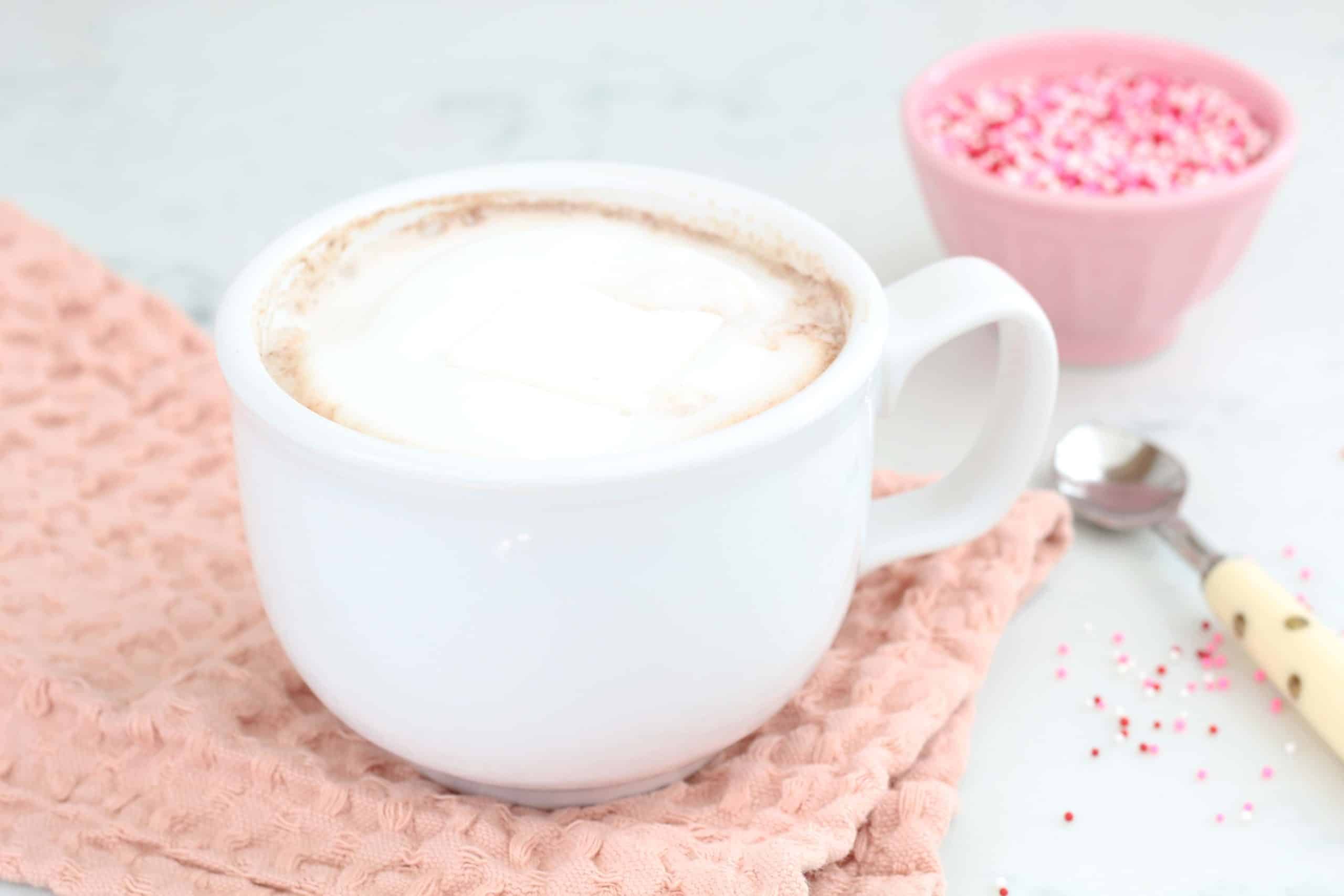 hot chocolate in white mug with pink sprinkles 