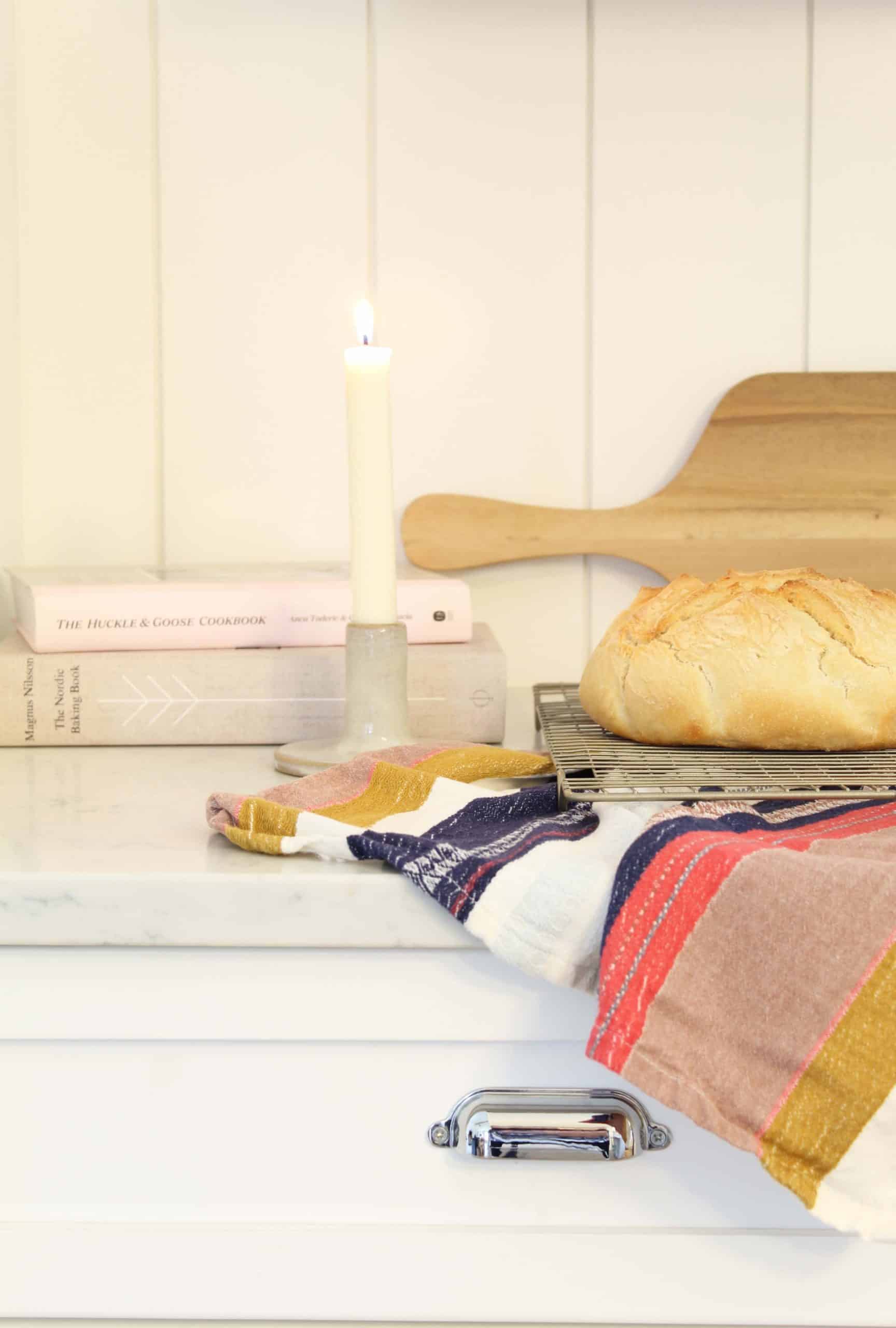 fresh sourdough bread, anthropologie kitchen towel, beeswax candle, huckle and goose cookbook