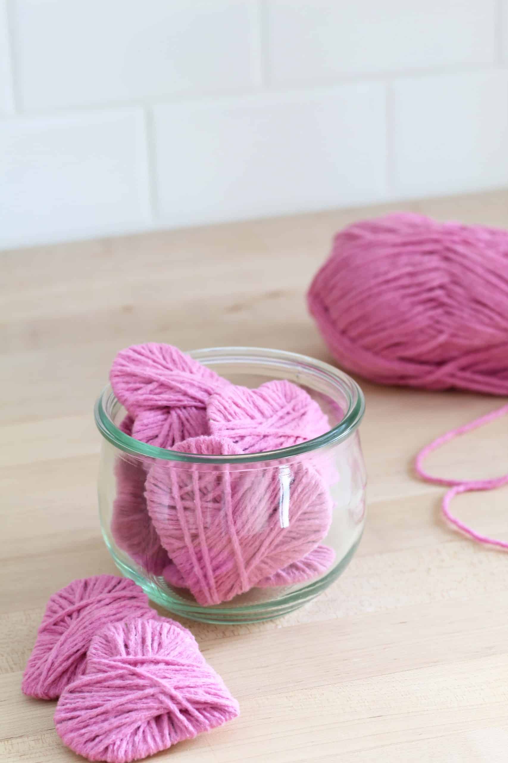 pink yarn hearts in glass jar, white subway tile backsplash and butcher block counter