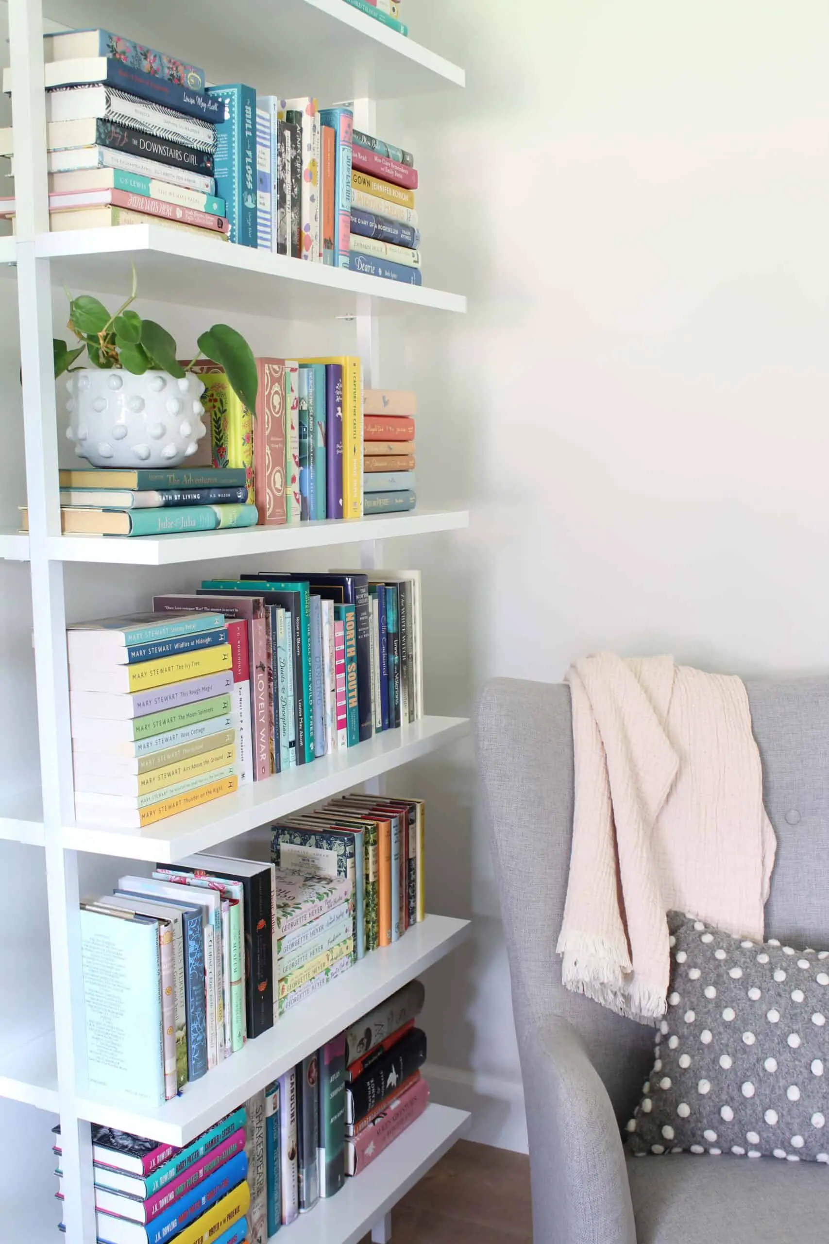 minimal white ladder bookshelf, gray chair with polka dot pillow