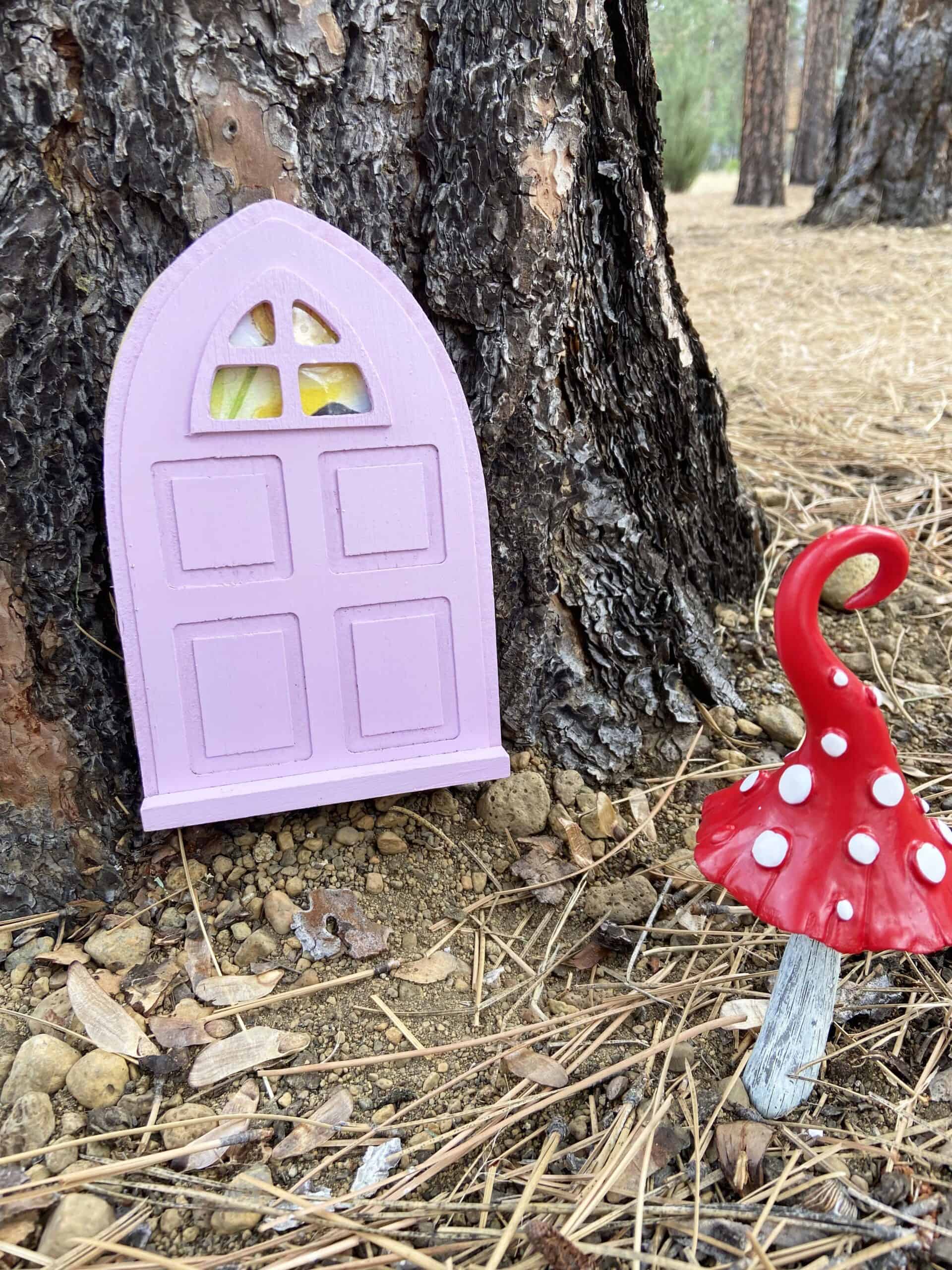 purple outdoor fairy door on a tree with red and white mushroom